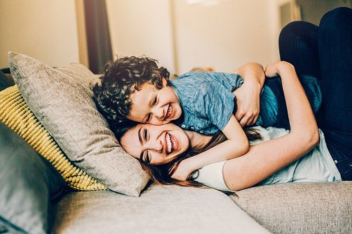 A mother wrapping her arms around her son in a warm embrace while also playing with him | Photo: Getty Images