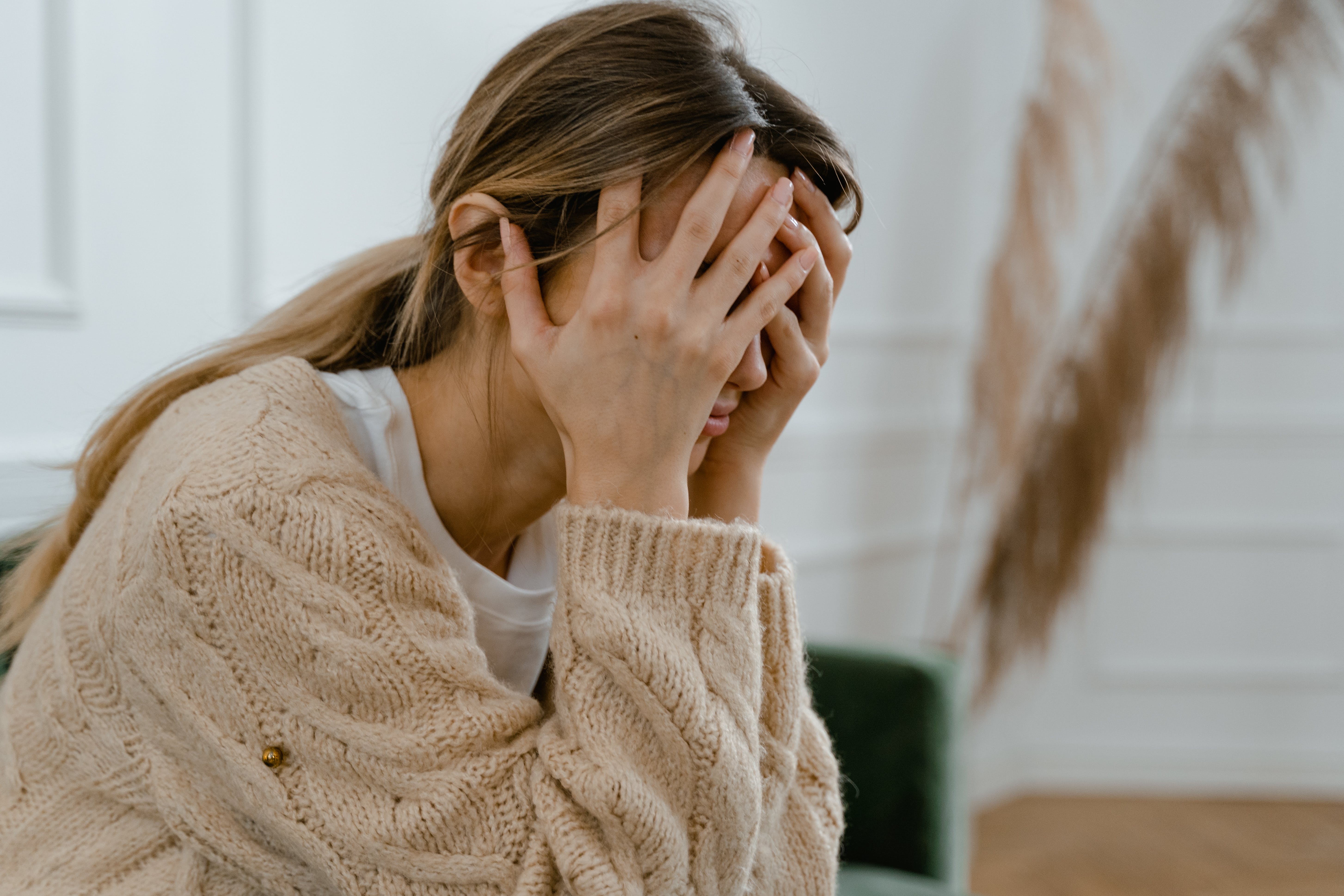 A stressed out woman sitting down while covering her face with her hands | Source: Pexels