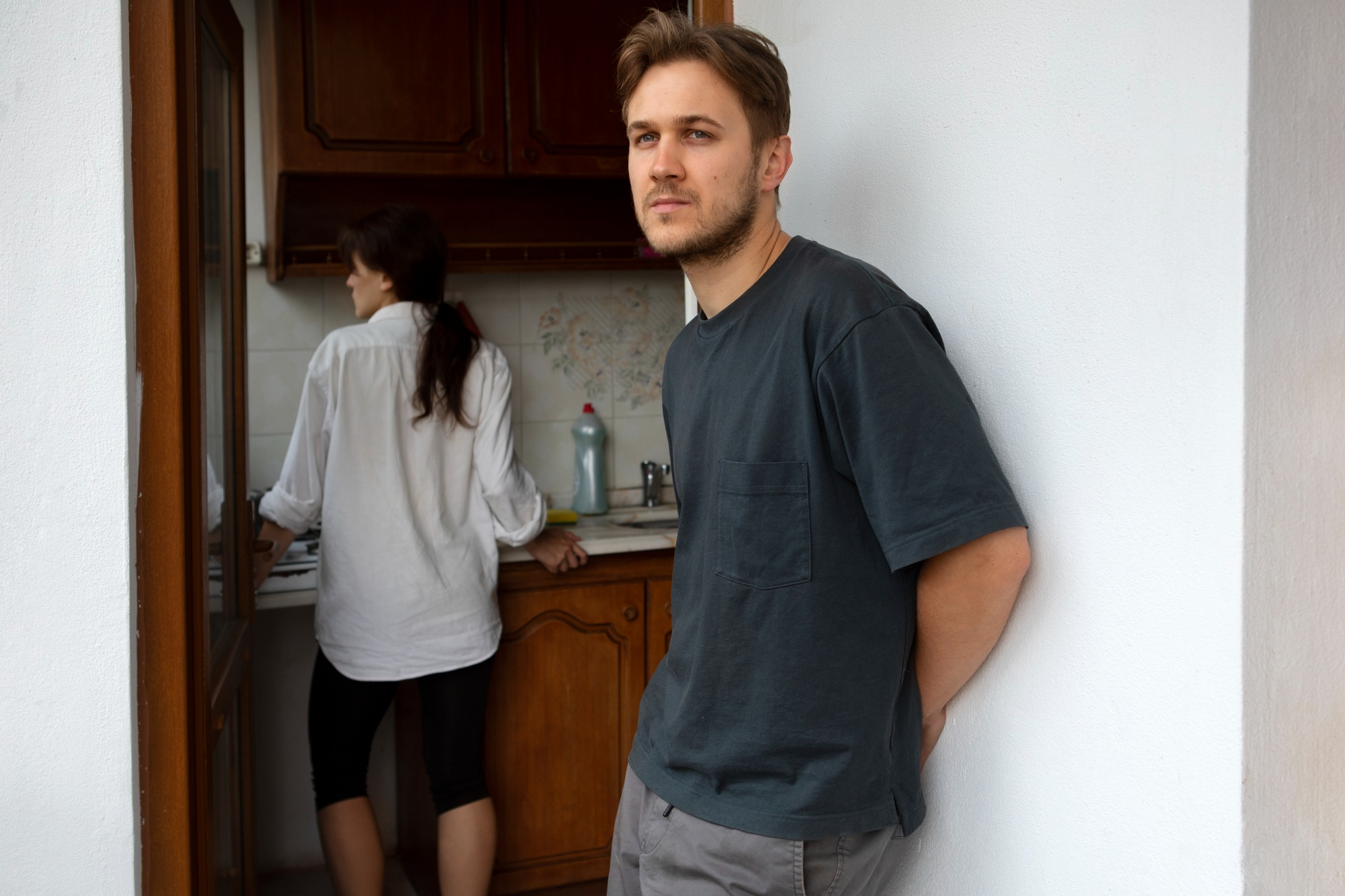 An upset man standing by the door while a woman stands in the kitchen | Source: Freepik