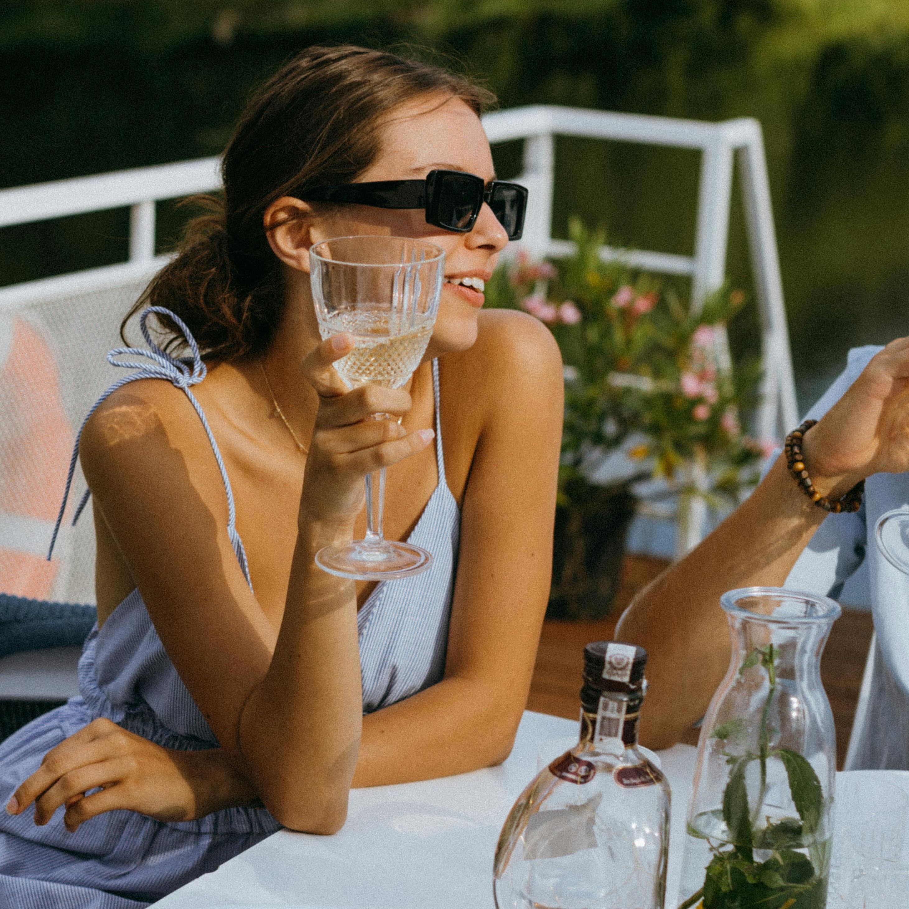 A woman aboard a yacht holds up a drink in celebration | Source: Pexels