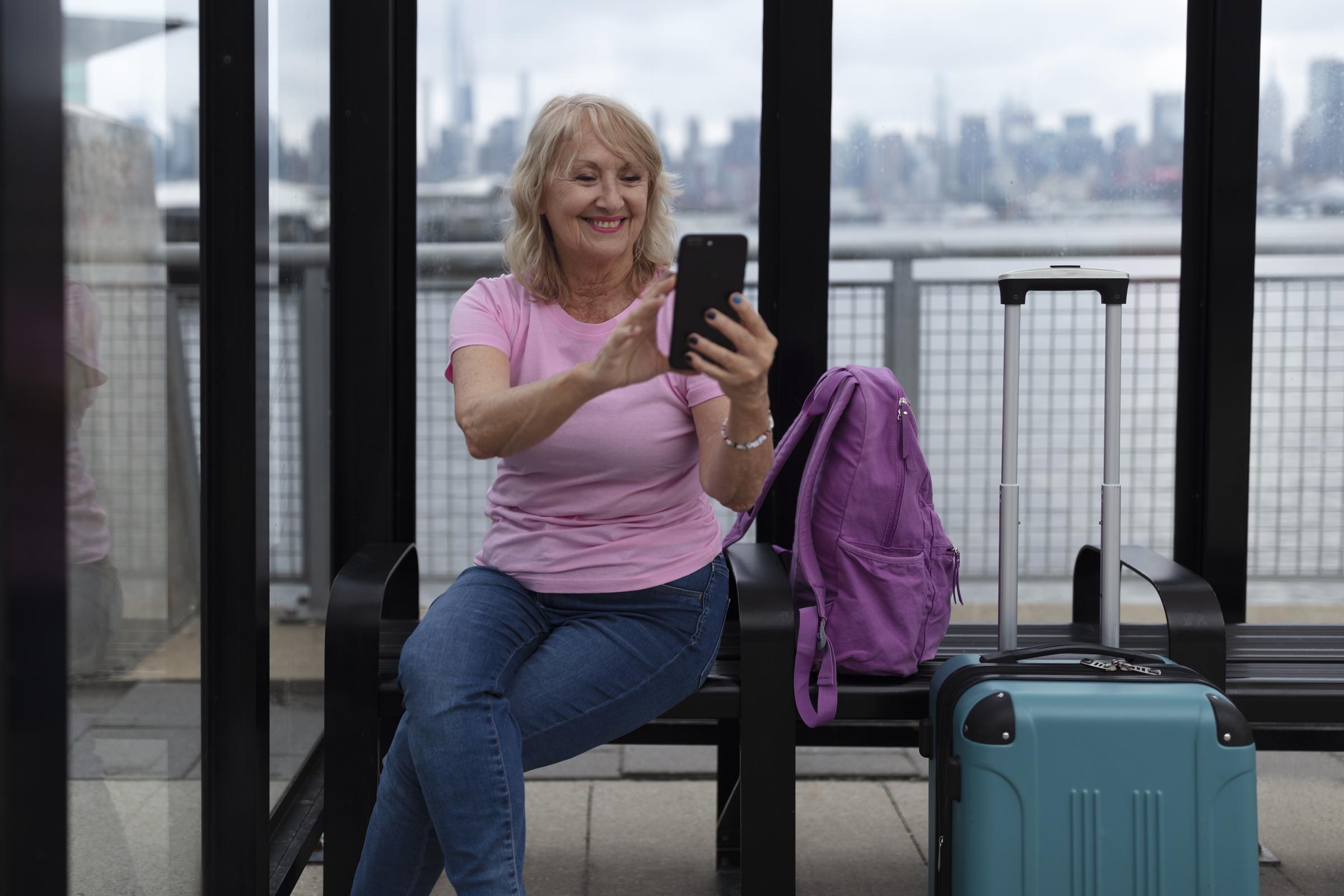 A senior woman sitting with her luggage | Source: Freepik