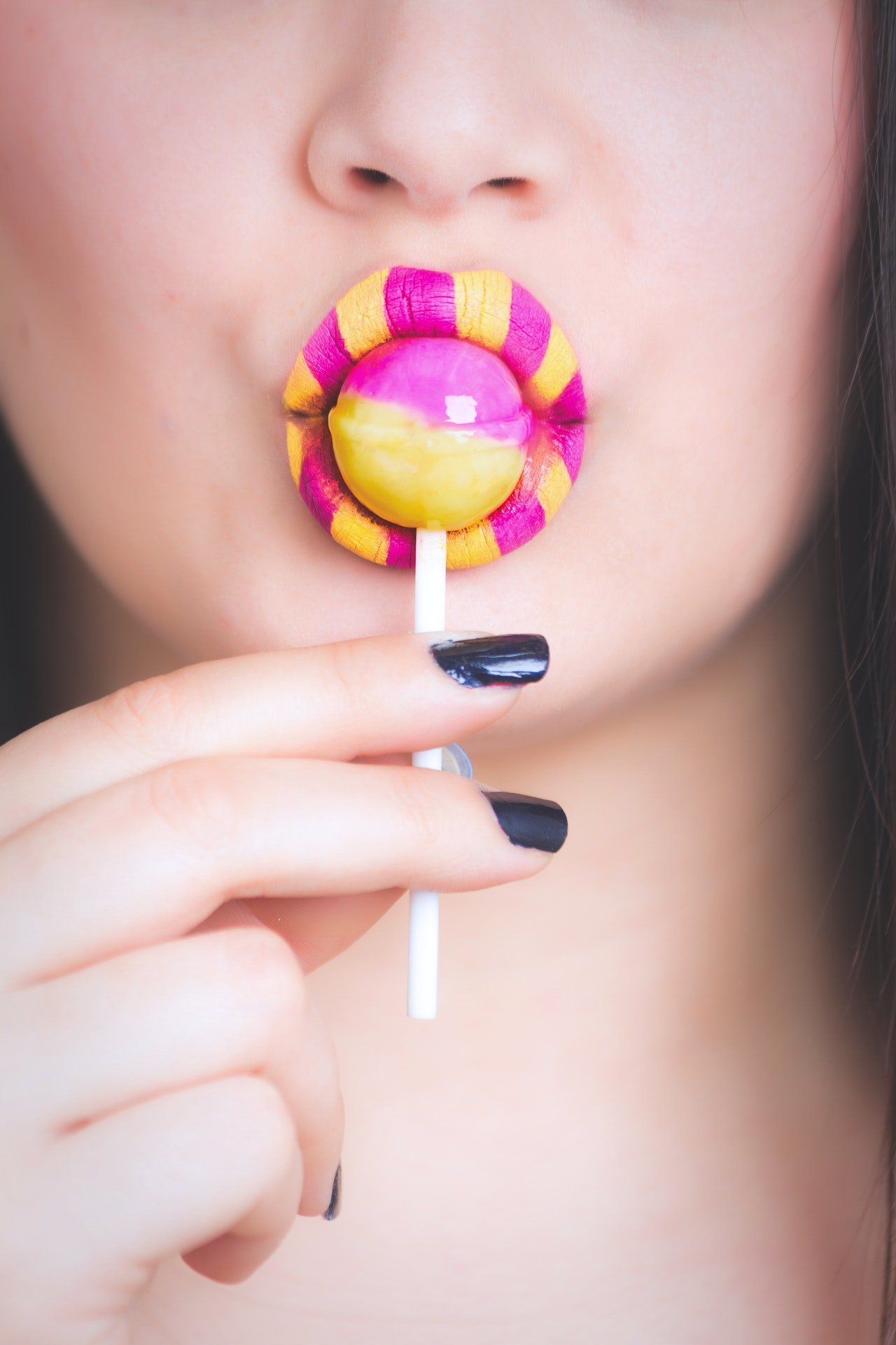 Photo of a woman licking lollipop | Photo: Pexels