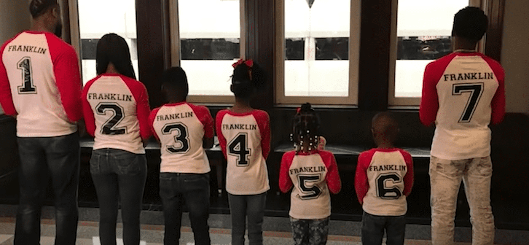 A family wears matching t-shirts with numbers on the back reflecting when they entered the family | Photo: Youtube/WFAA