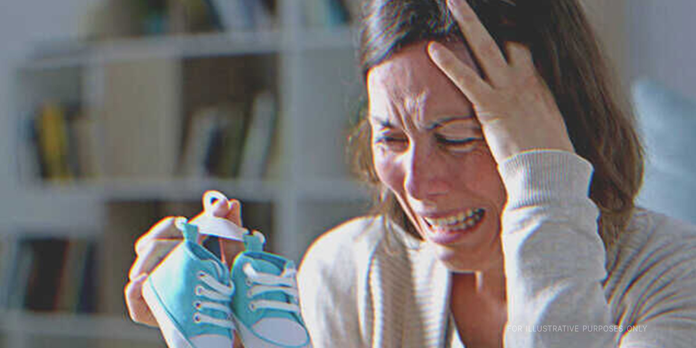 Grieving mother holding a pair of blue shoes | Source: Shutterstock