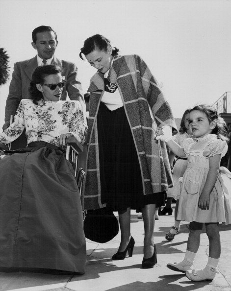 Actress Susan Peters in a wheelchair, talking to actress and singer Judy Garland and her daughter Liza Minnelli, circa 1950. | Source: Getty Images