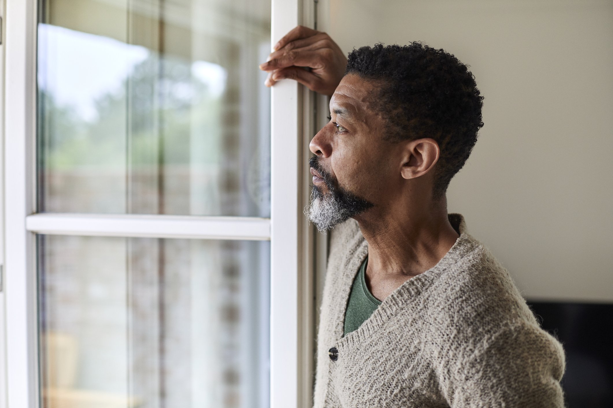 A worried man looks out the window in deep thought. | Photo: Getty Images