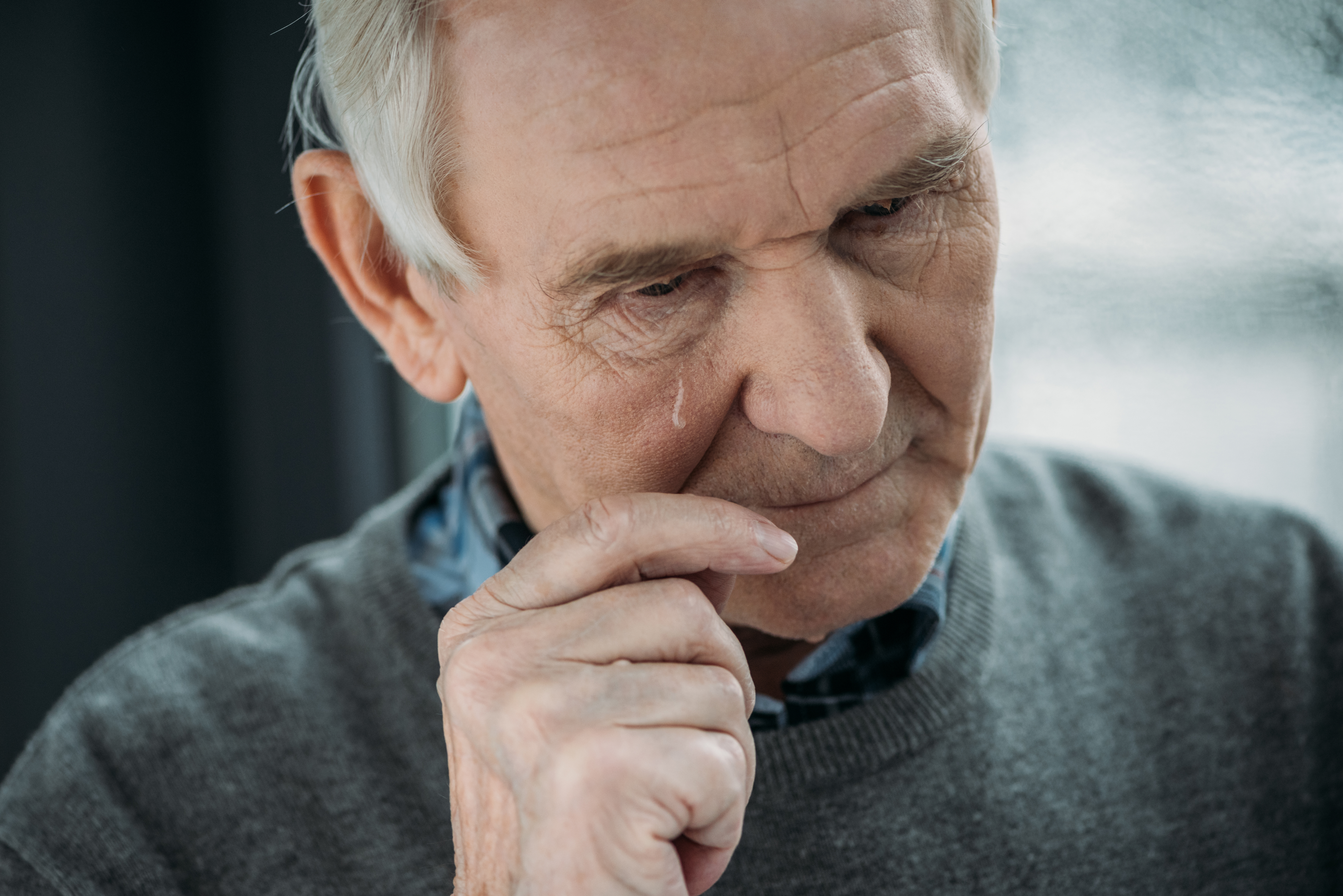 Older man crying and wiping away a tear | Source: Shutterstock