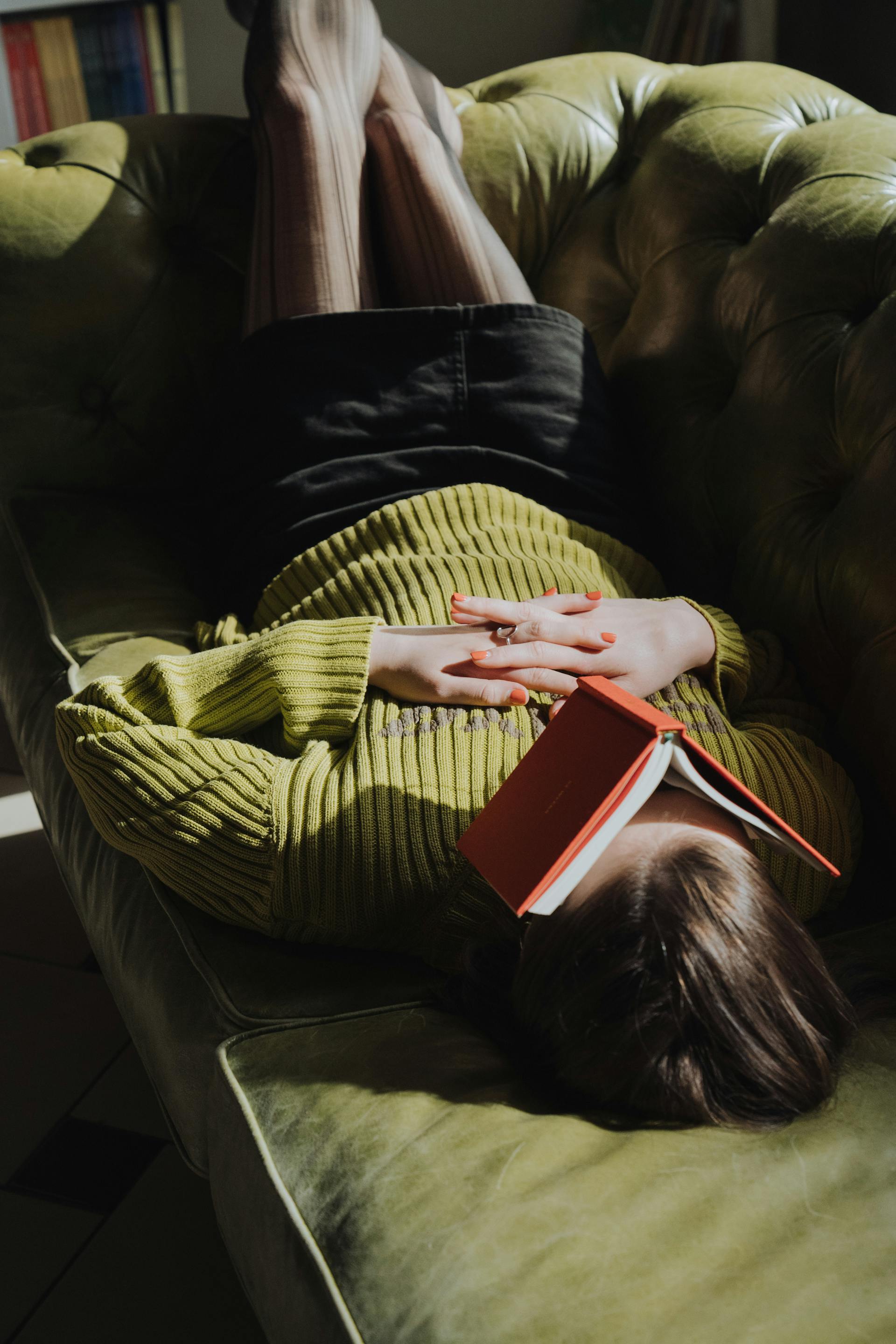 A woman laying on a couch with a book | Source: Pexels