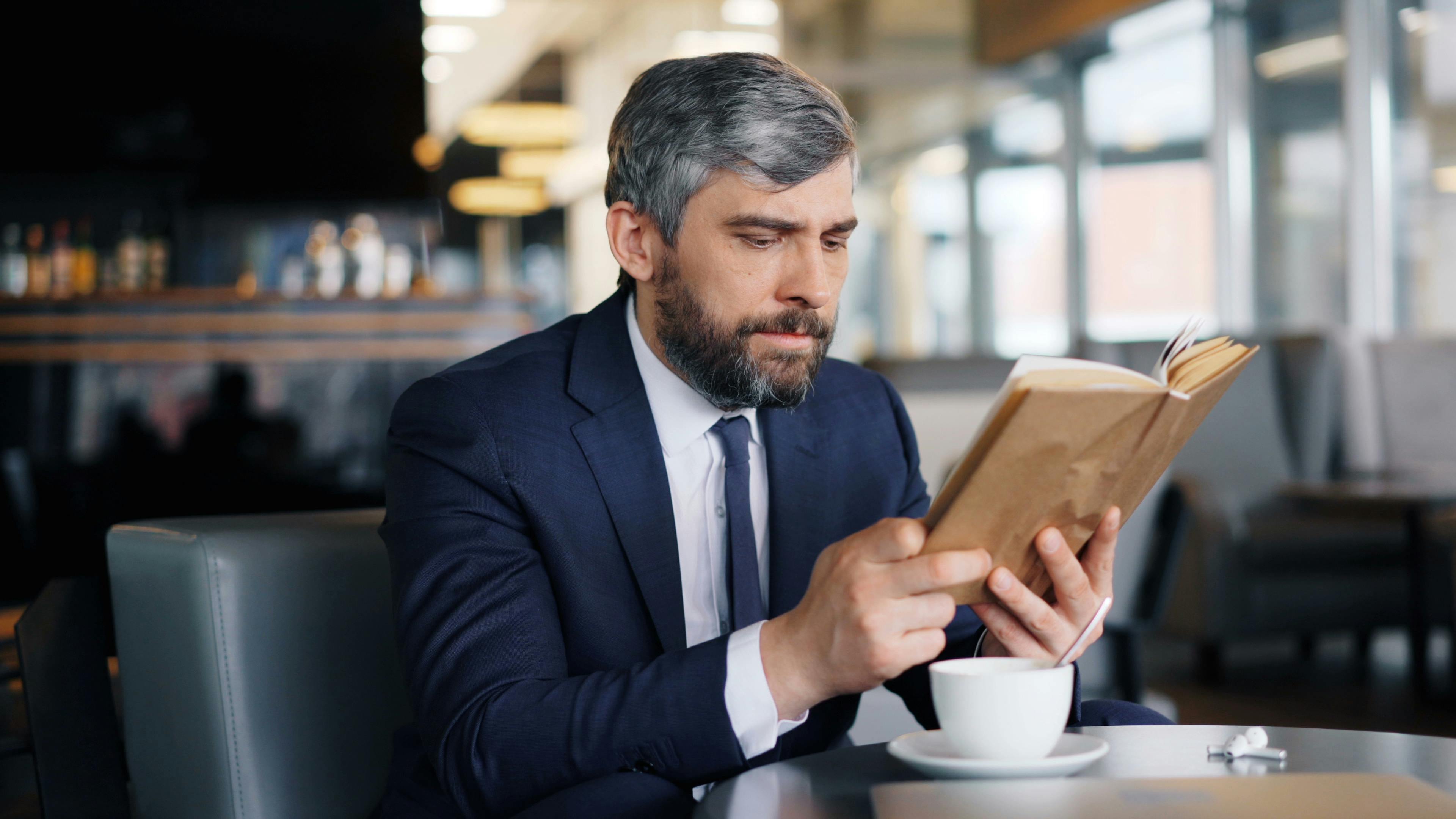 A man with a book in a cafe | Source: Pexels