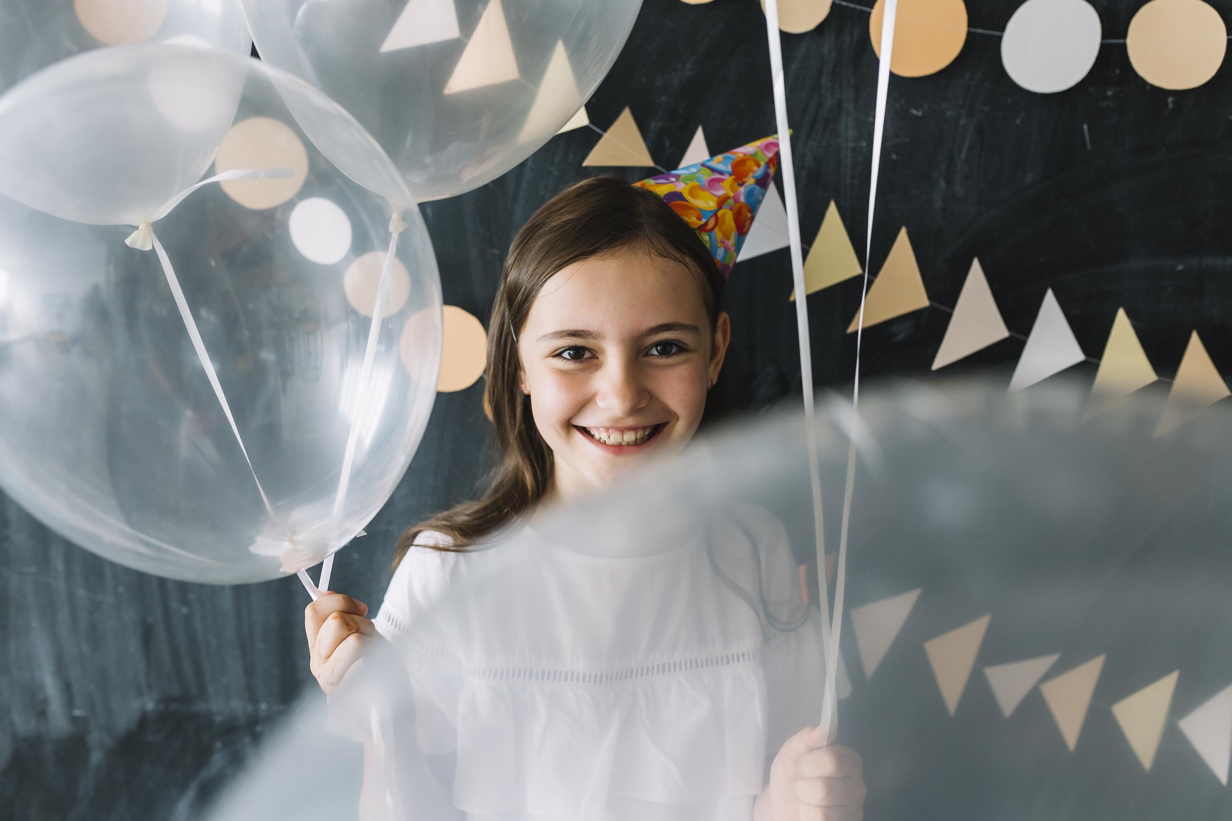 Smiling little girl holding balloons | Source: Freepik