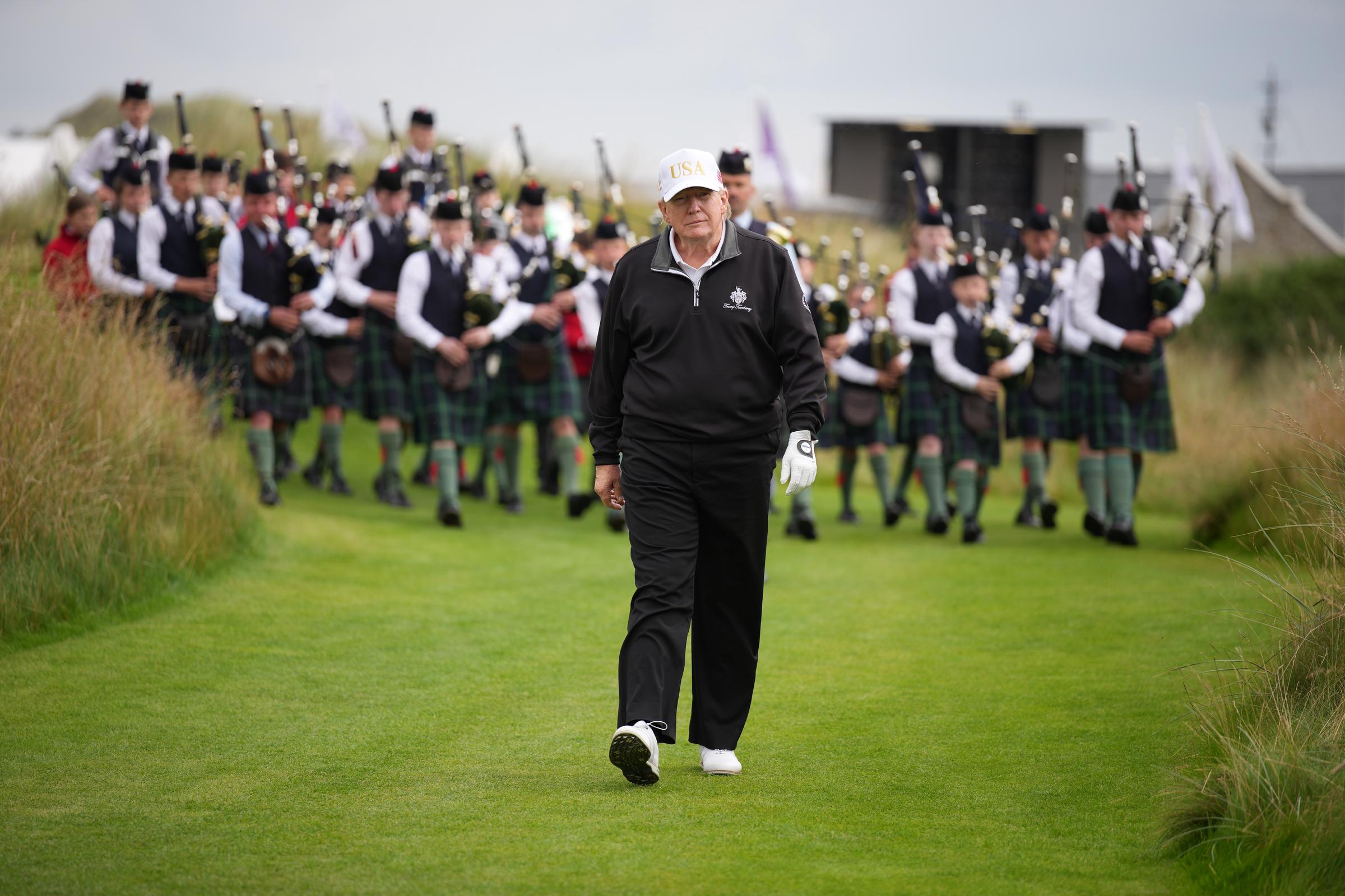 Donald Trump reacts as he walks on the course followed by a band at the ribbon-cutting ceremony at a new 18-hole course at Trump International Golf Links on July 29, 2025 in Balmedie, near Aberdeen, Scotland | Source: Getty Images