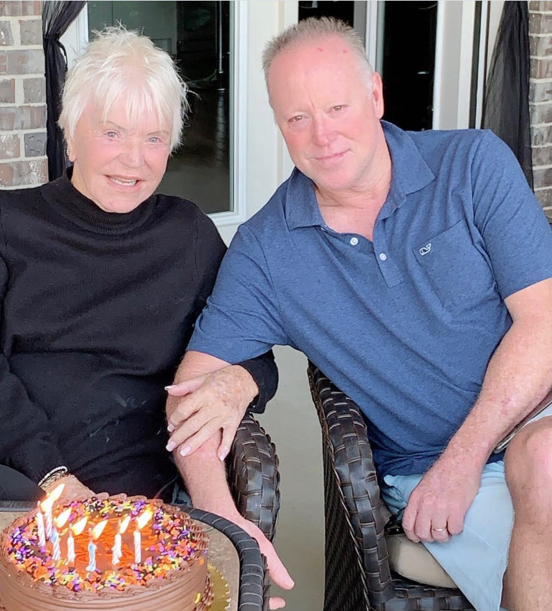 Mike Norris sits beside his mother, Dianne Holechek, as they smile over a birthday cake lit with candles. | Source: Instagram/iammikenorris