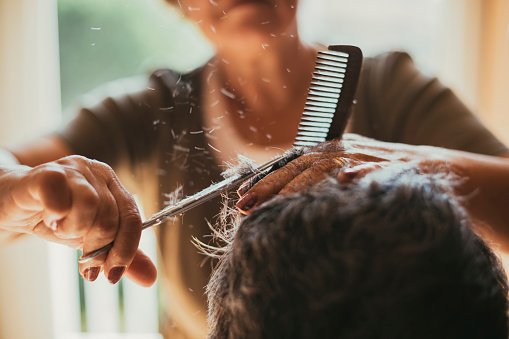 Une coiffeuse coupant les cheveux de ses clients. | Photo : Getty Images