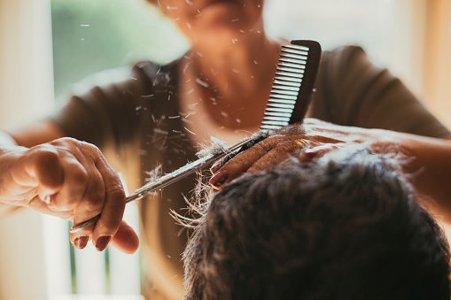 Une coiffeuse coupant les cheveux de ses clients. | Photo : Getty Images