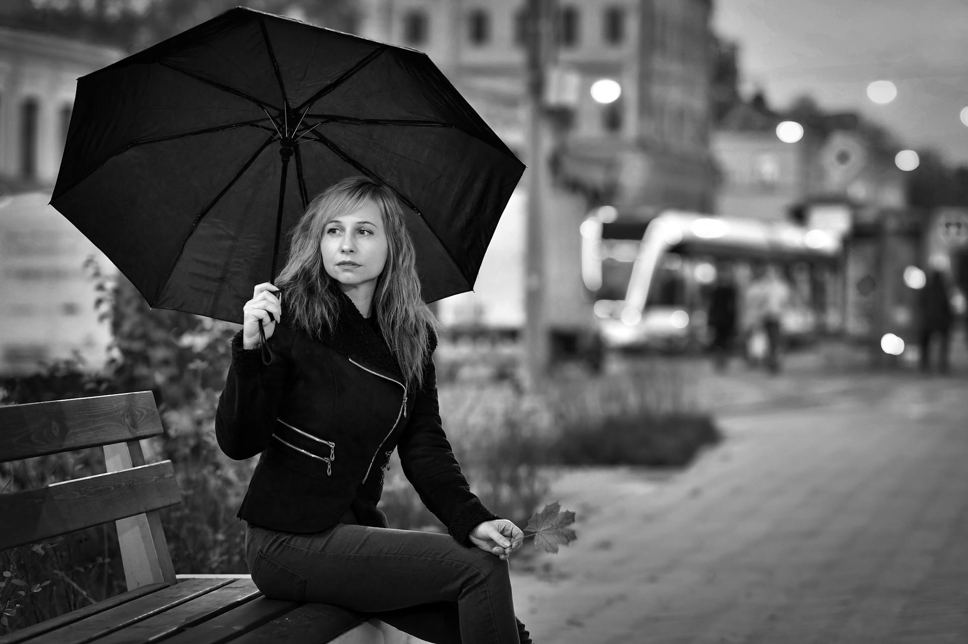 A woman sitting on the bench holding an umbrella | Source: Pexels