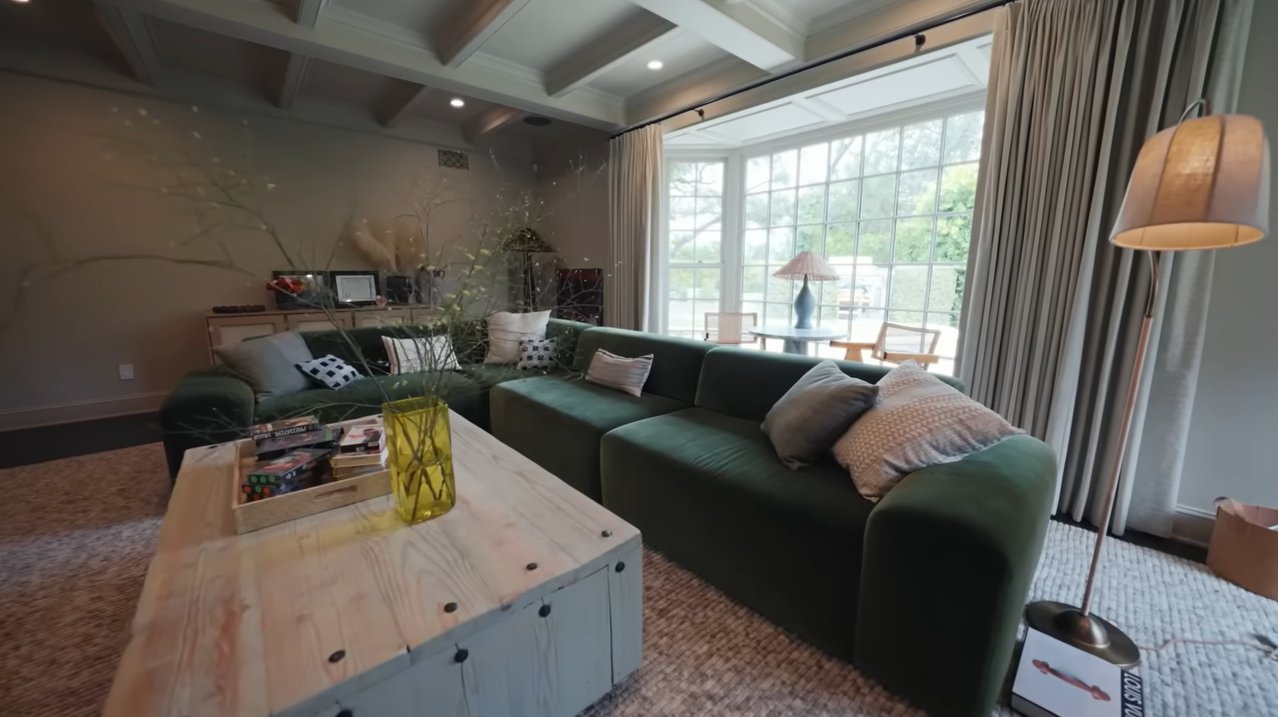 Ultimate family movie hub! Palmer's media room centers around a custom green velvet sectional couch designed in true earth-sign fashion. | Source: YouTube/@Archdigest