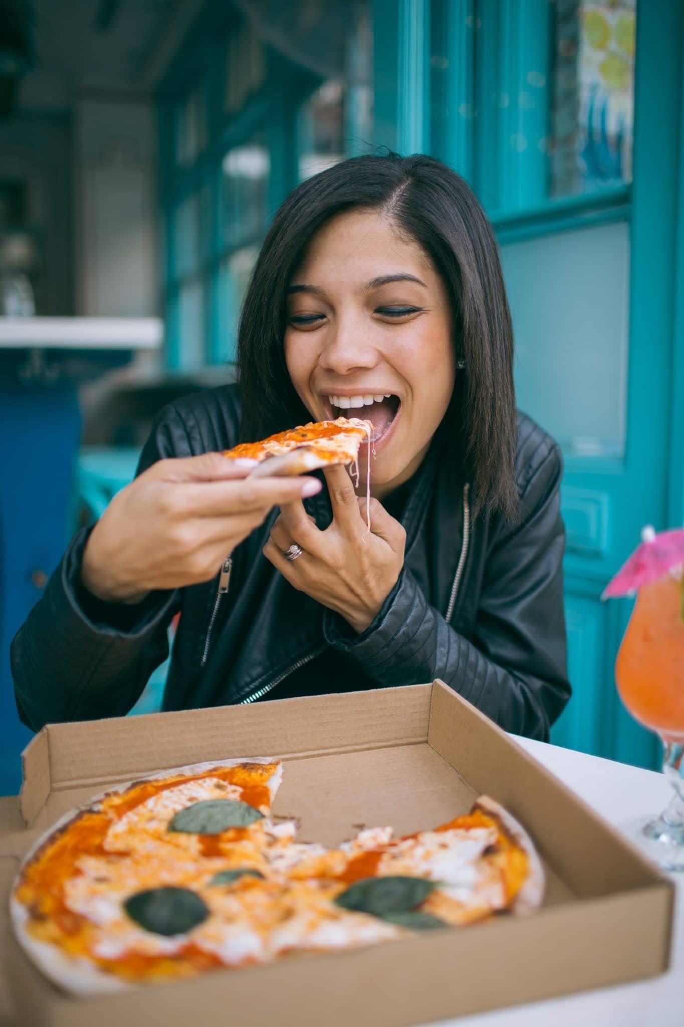 Chica comiendo pizza. | Foto: Pexels
