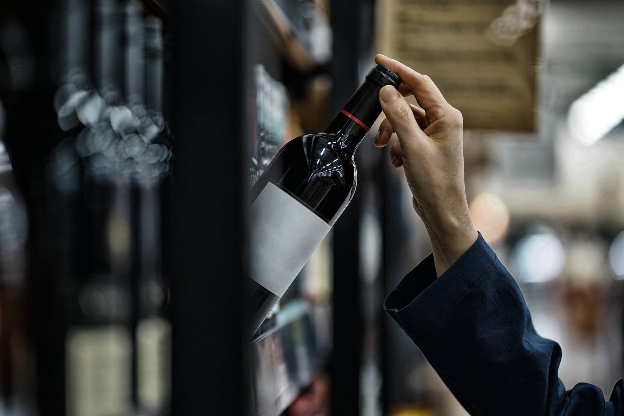 Woman choosing wine bottle in liquor store | Source: Getty Images