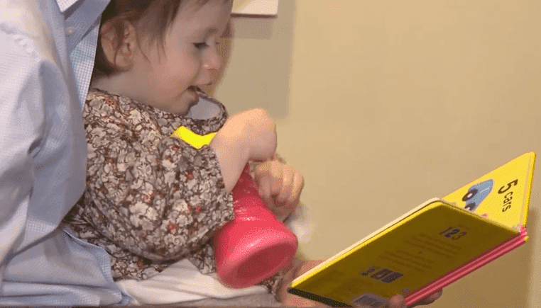 Samantha on her father's lap enjoying a children's book | Photo: ABC 7