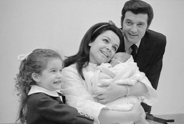 Annette Funicello cuddles her newborn son, Jack, Jr., at St. Joseph's Hospital., with her husband, Jack Gilardi, and their daughter, Gina, on February 13, 1970. | Source: Getty Images