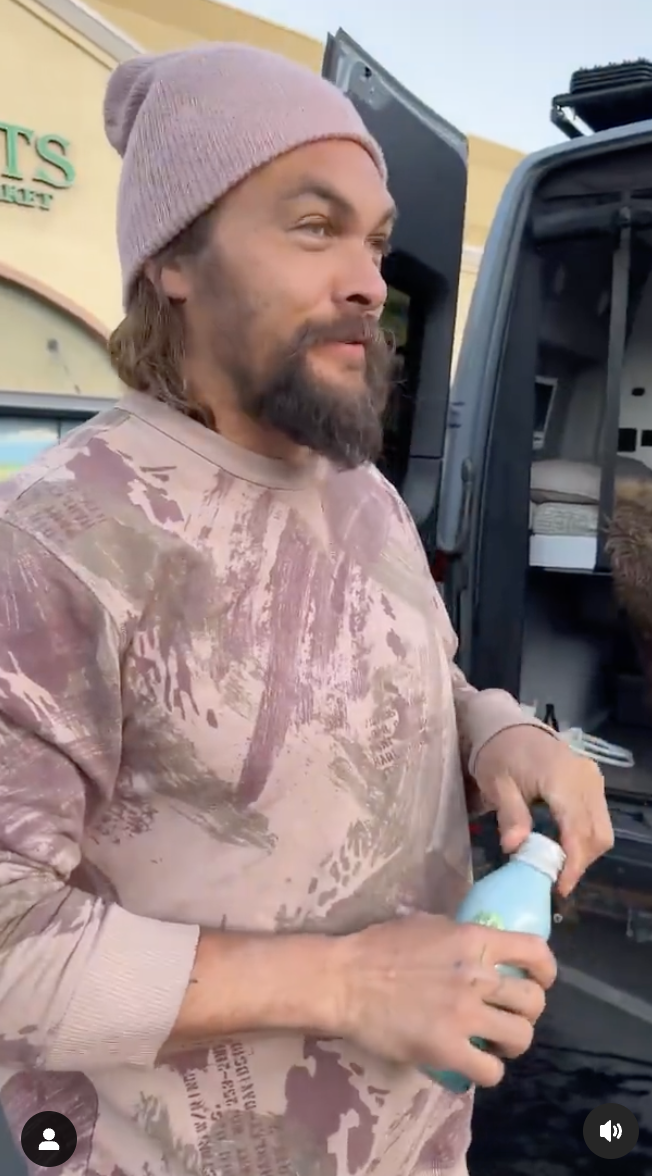 Jason Momoa pictured with a bottle in his hand, standing outside his van. | Source: instagram.com/prideofgypsies/