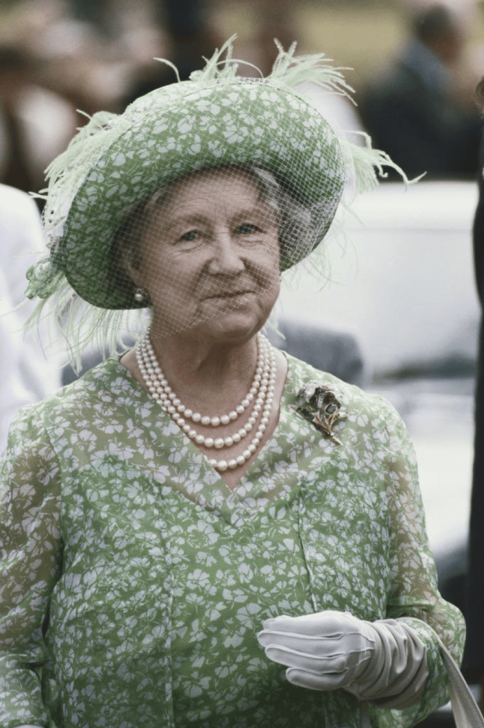 Die Mutter der Königin (1900 - 2002), in einem grünen Blumenkleid mit Federn und Netz bei der Sandringham Flower Show am Sandringham Estate in Norfolk, England, 28. Juli 1982. | Quelle: Getty Images