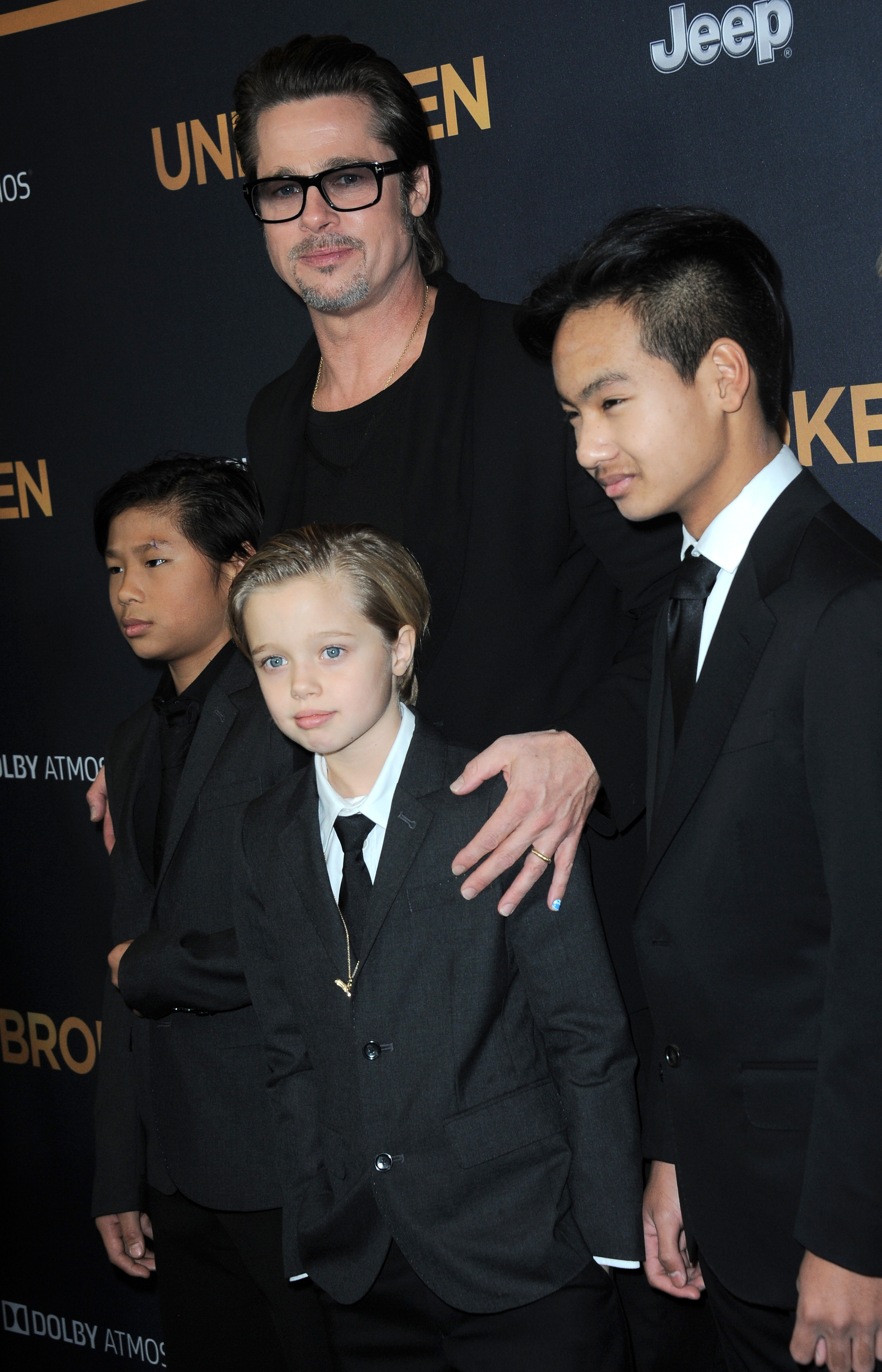Brad Pitt arrives at the Unbroken premiere with Shiloh and her brothers, all dressed in sharp black suits. Standing front and center, Shiloh Jolie-Pitt wears a tie and blazer, embracing a polished, boyish look. The red carpet moment highlights her confidence and signature style at the time.