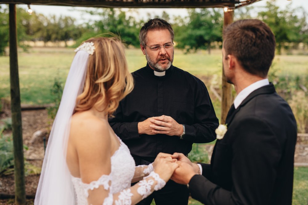 Male priest marries a couple in lovely outdoor wedding ceremony. | Photo: Shutterstock