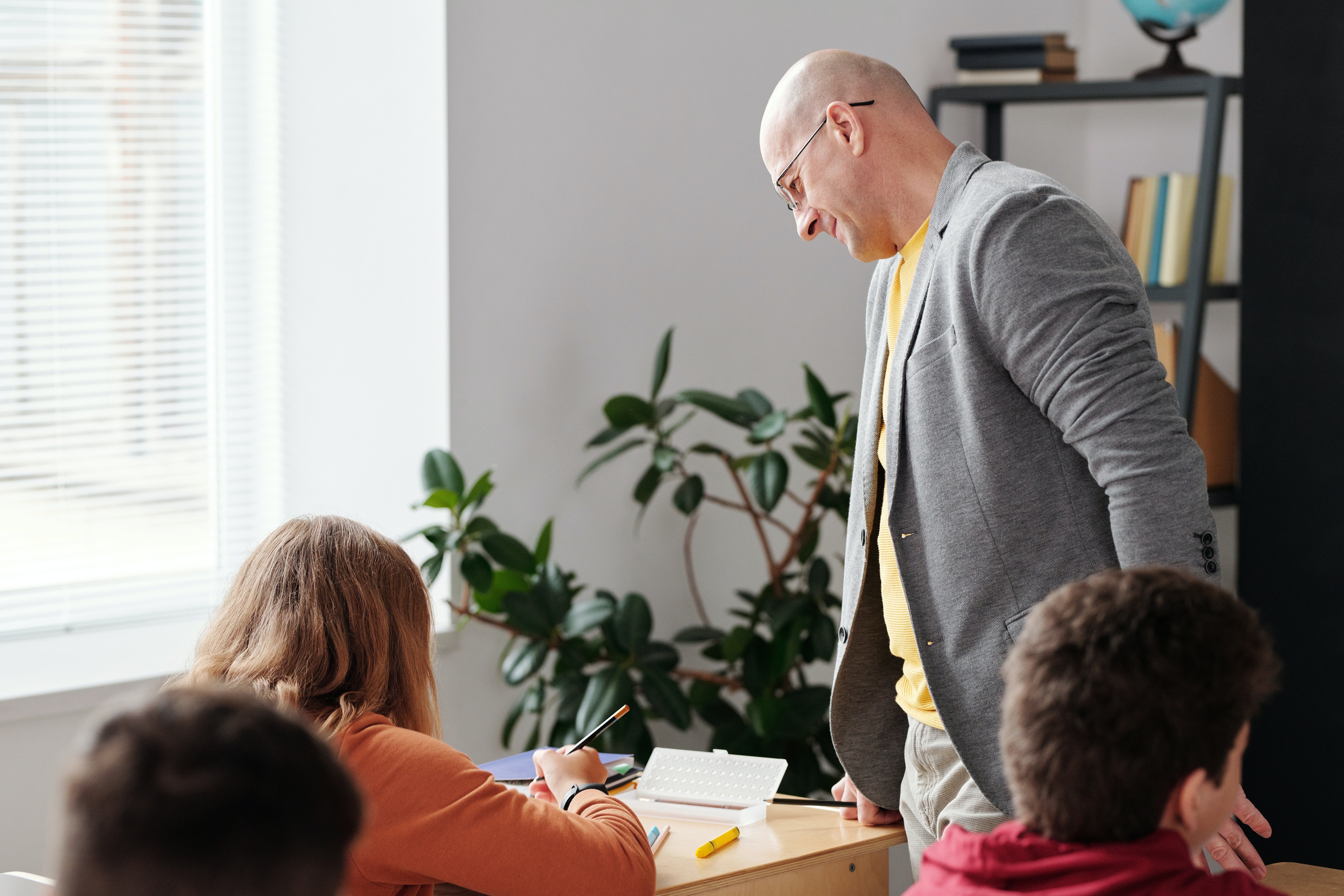 A teacher looking over his student | Photo: Pexels 