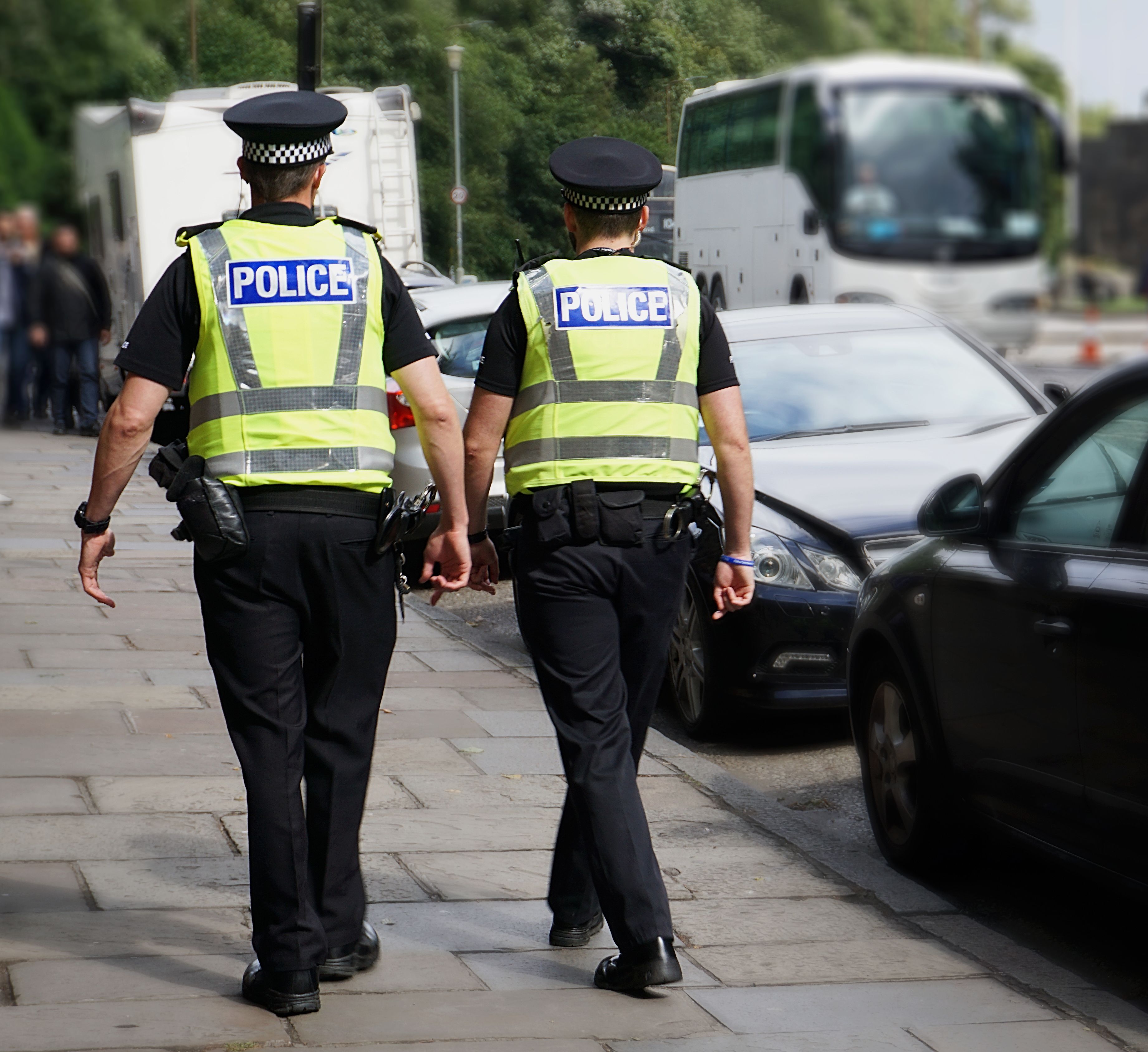 Zwei Polizisten gehen an parkenden Autos vorbei. | Quelle: Shutterstock