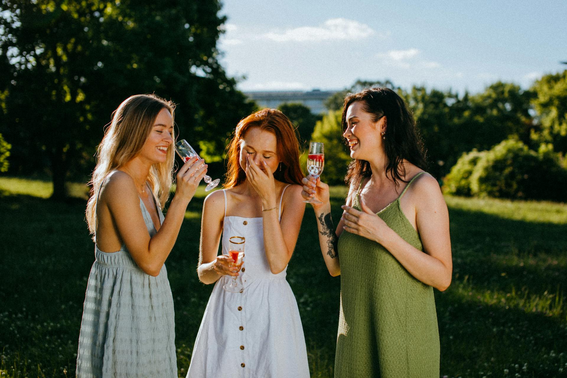 Three young women laugh while enjoying their drinks | Source: Pexels