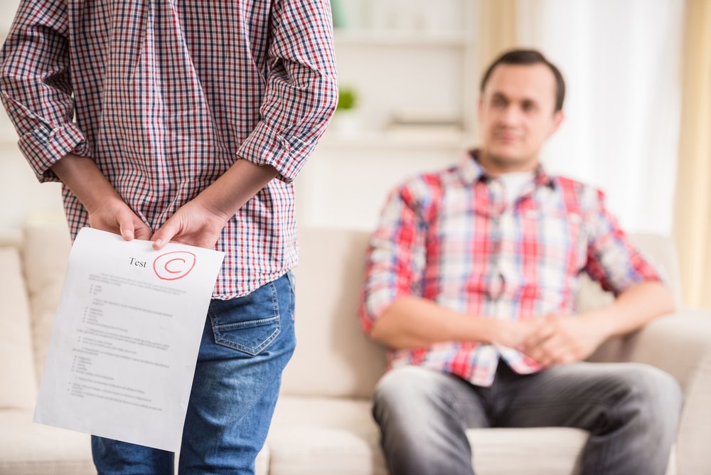 Junge, der sich hinter dem hinteren schlechten Testergebnis versteckt. I Quelle: Shutterstock