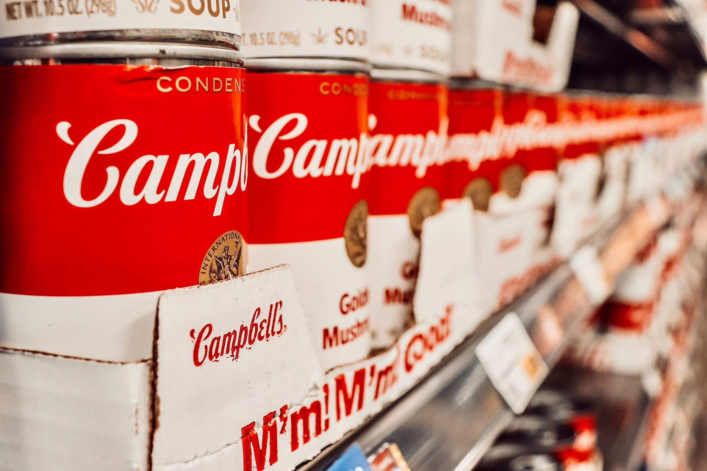 Soup cans stacked on a supermarket shelf | Source: Unsplash