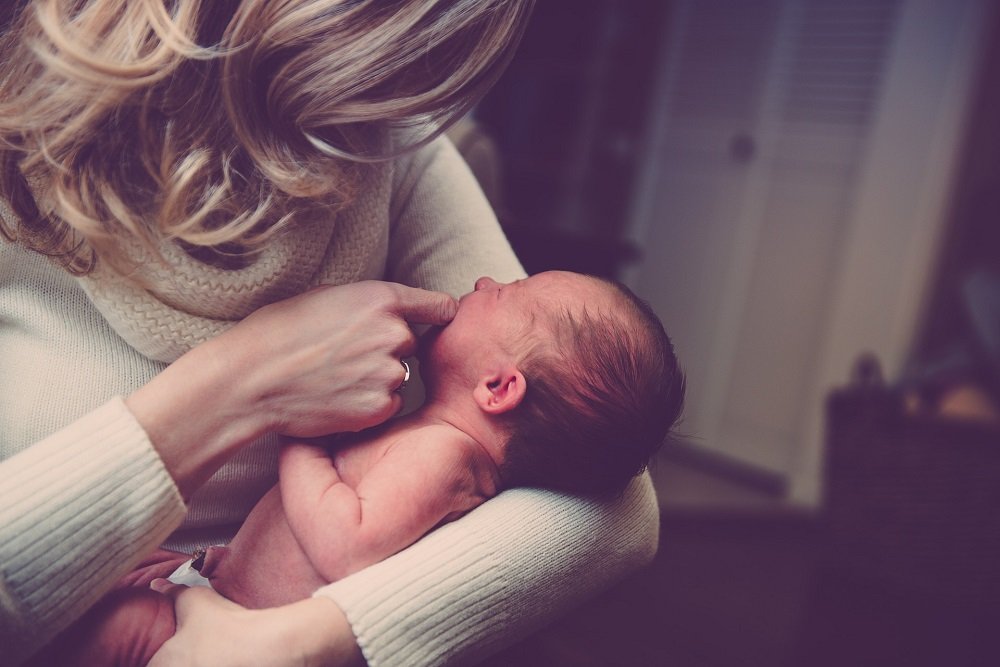 A mother holding a little baby and lovingly playing with him. | Photo: Pixabay.