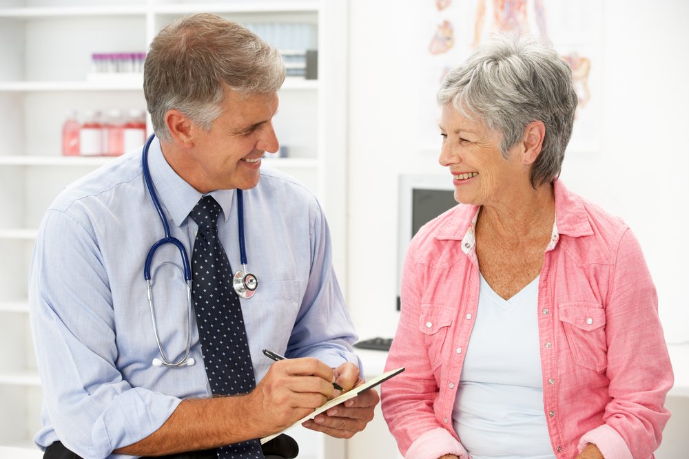 A senior woman sitting and discussing with his doctor. | Photo: Shutterstock.