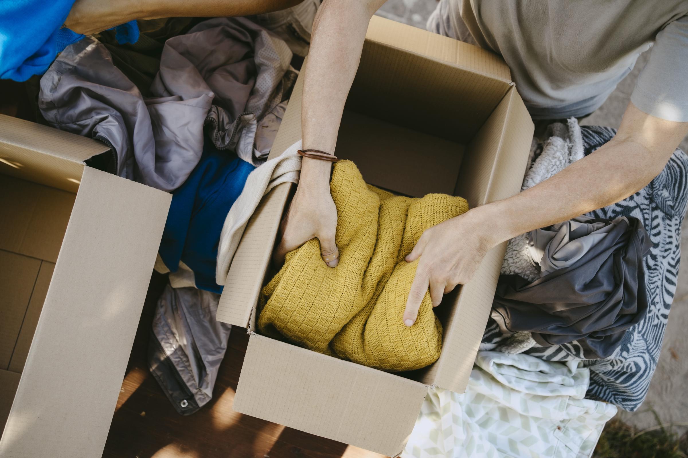 A man packing clothes into a donation box | Source: Getty Images