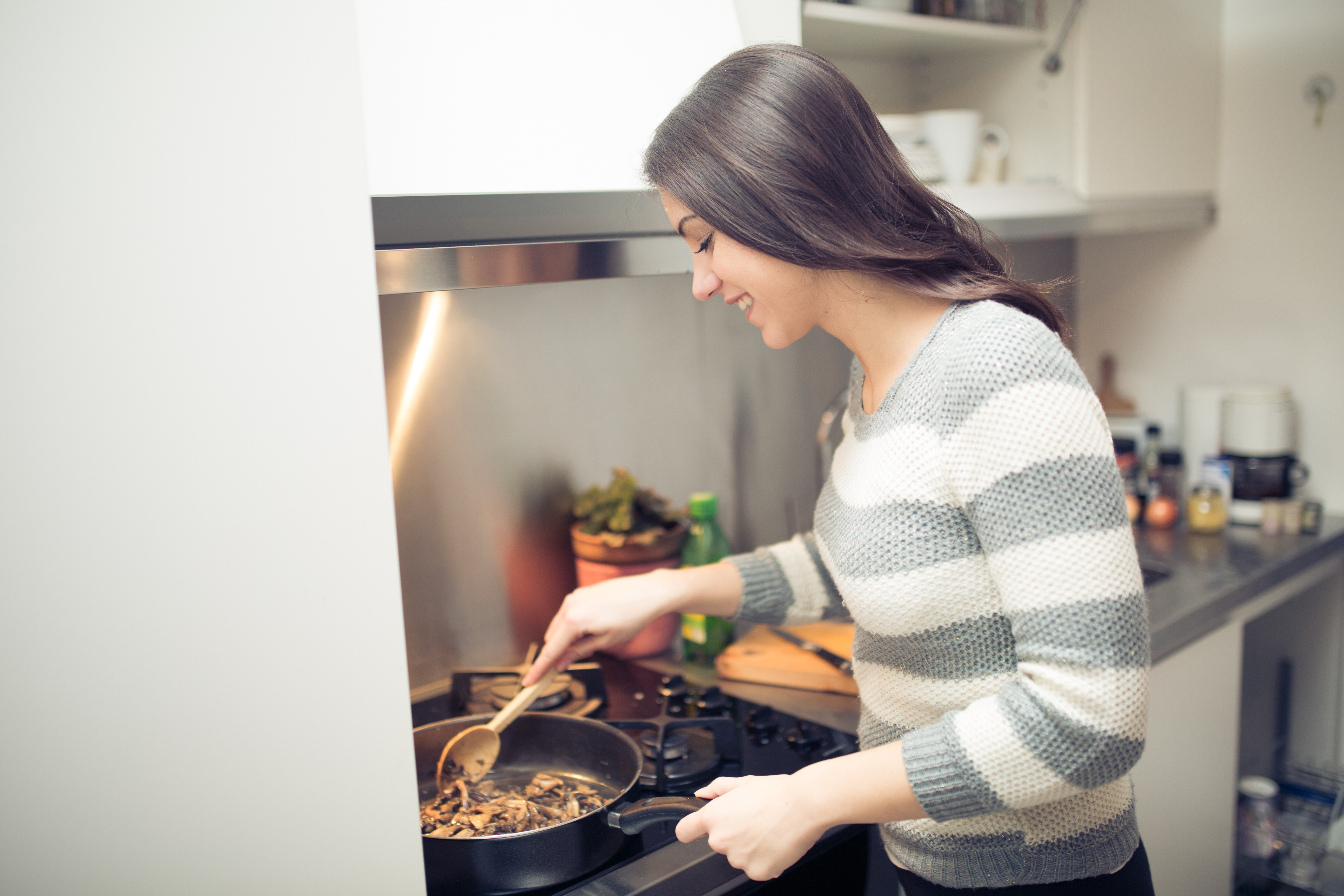 Young woman cooking healthy diet food in the home kitchen. | Source: Shutterstock