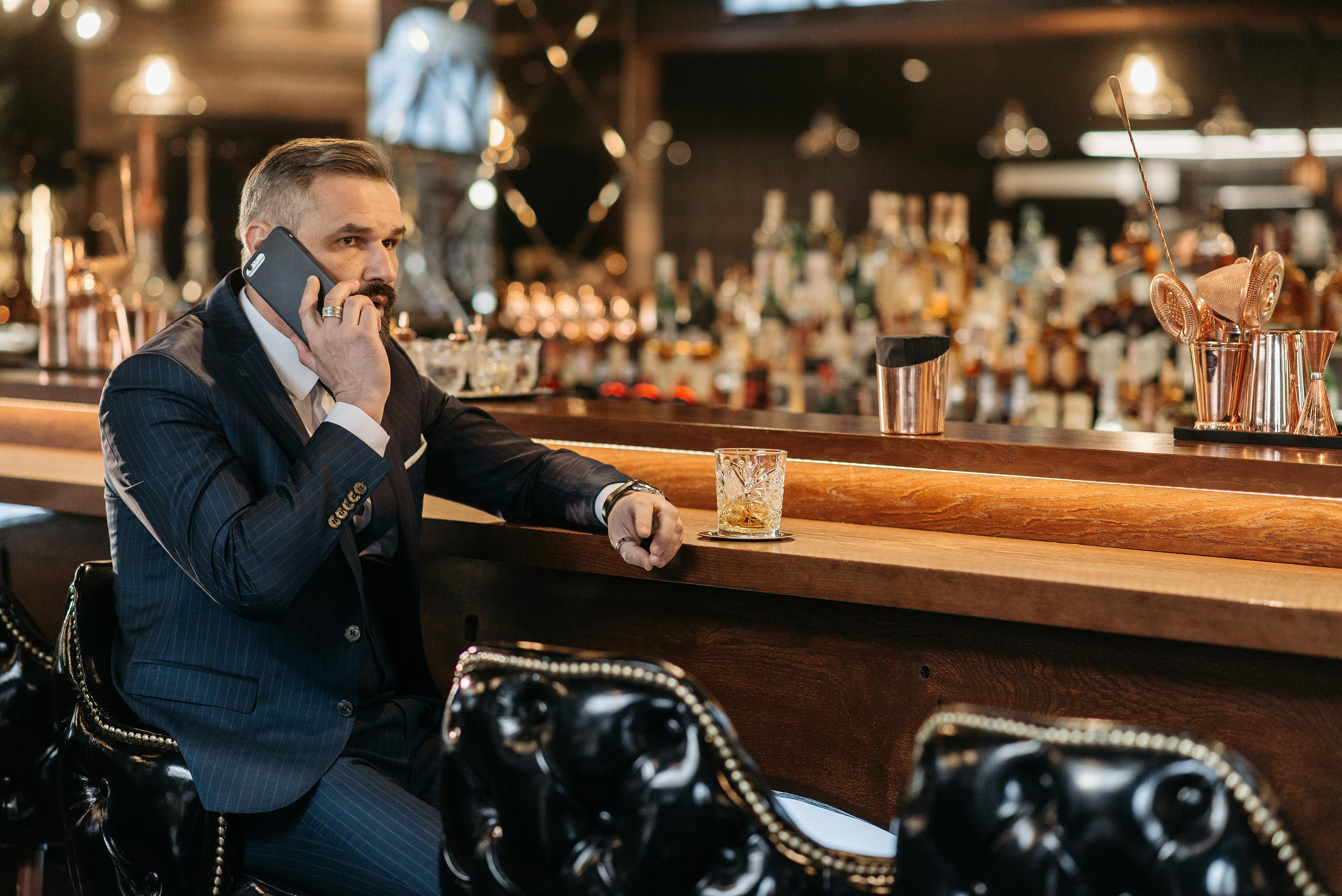 A man speaking on the phone while drinking at a bar | Source: Pexels