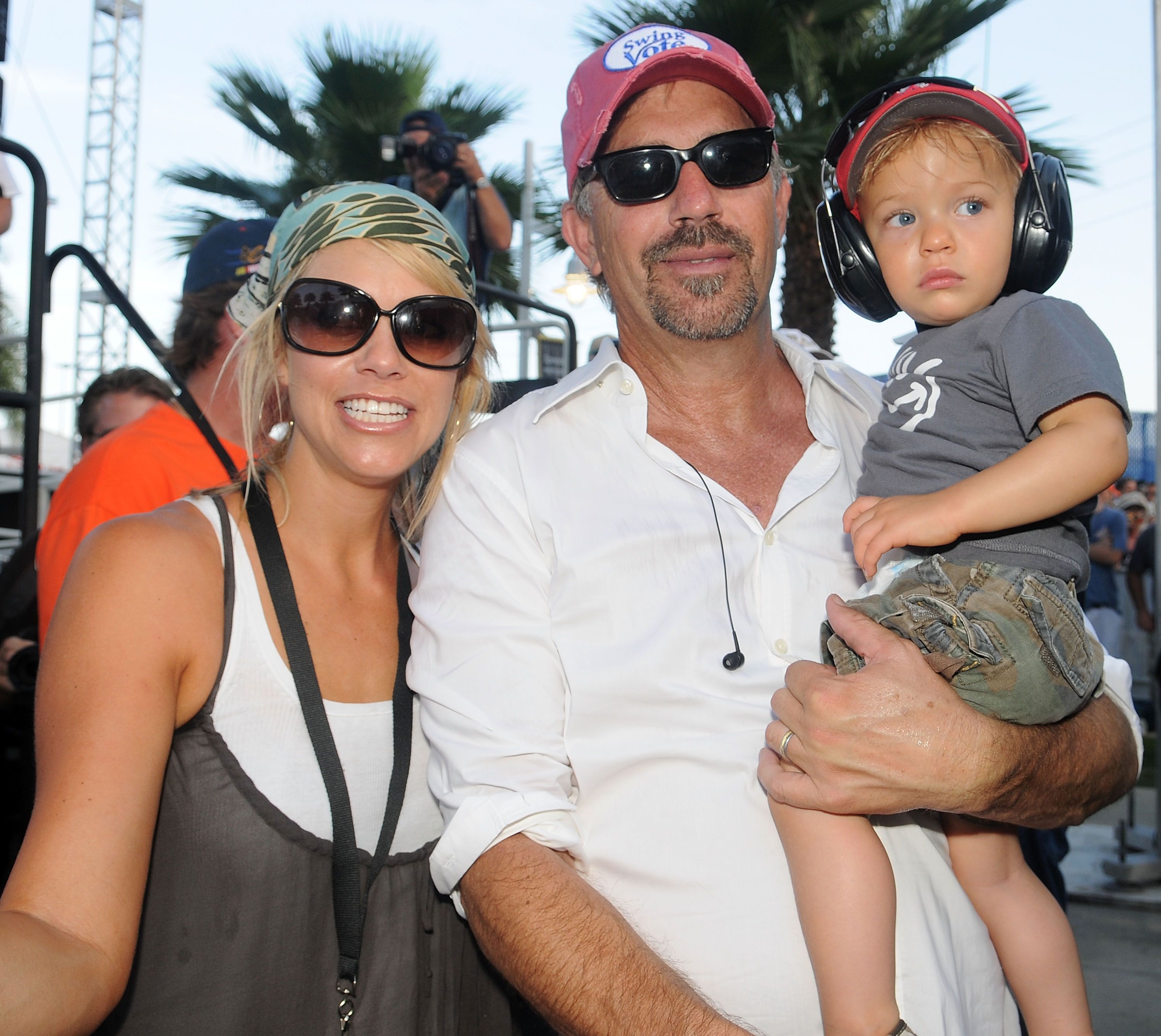 Kevin Costner (C) poses with his wife Christine Baumgartner (L) and son Cayden Costner during the Sprint Fan Zone before the NASCAR Sprint Cup Series Coke Zero 400 at Daytona International Speedway on July 5, 2008 in Daytona Beach, Florida | Source: Getty Images