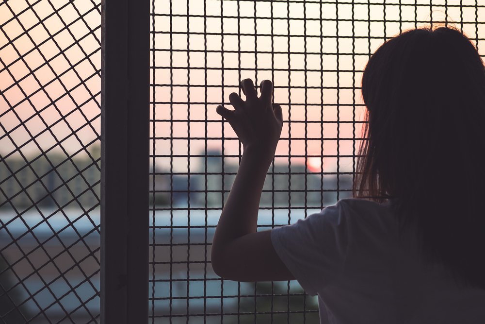 Woman's hand grabs the fence, concept of imprisonment. | Photo: Shutterstock
