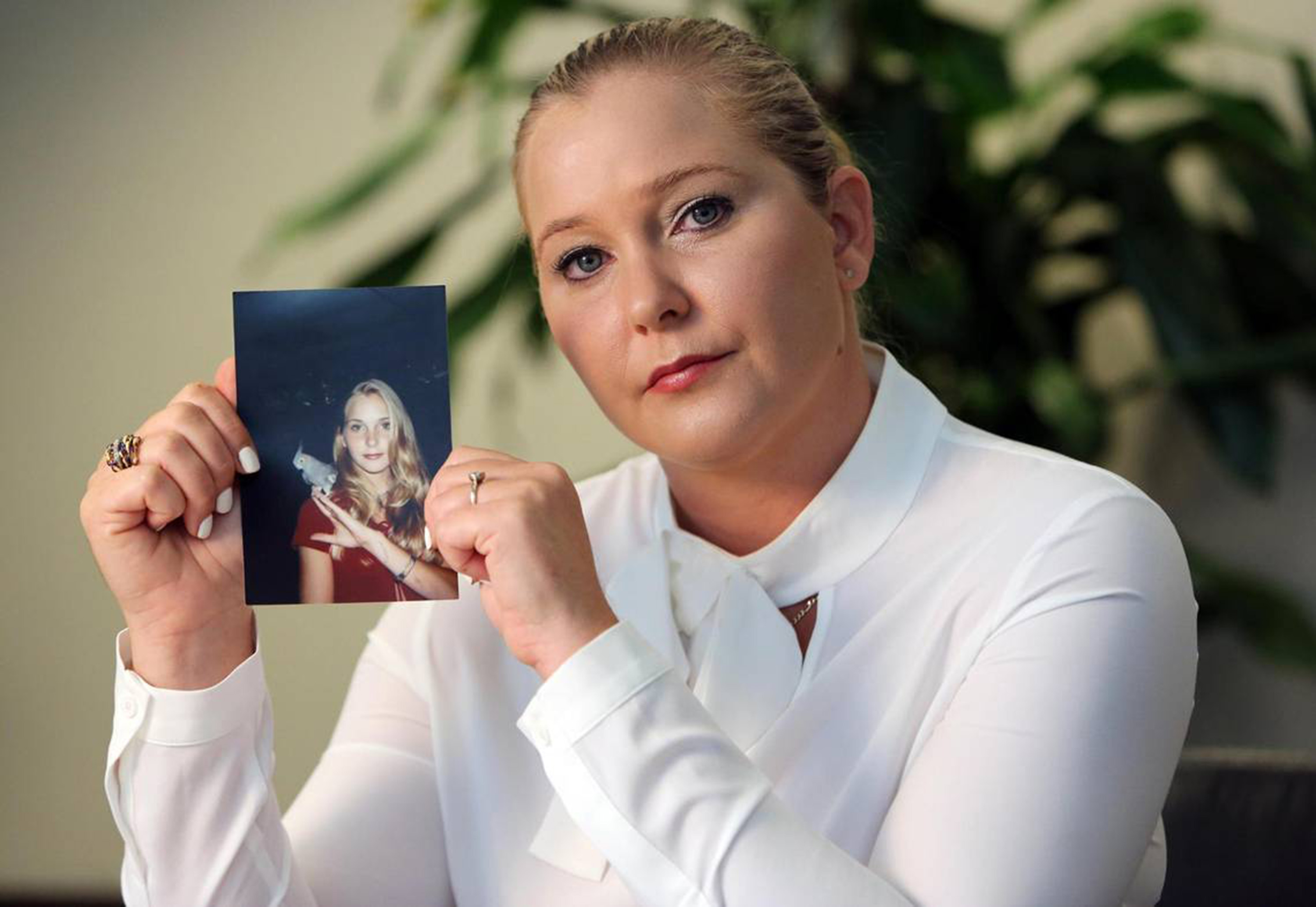 Virginia Giuffre holding a photo of herself at age 16, when she says Jeffrey Epstein began sexually abusing her. | Source: Getty Images