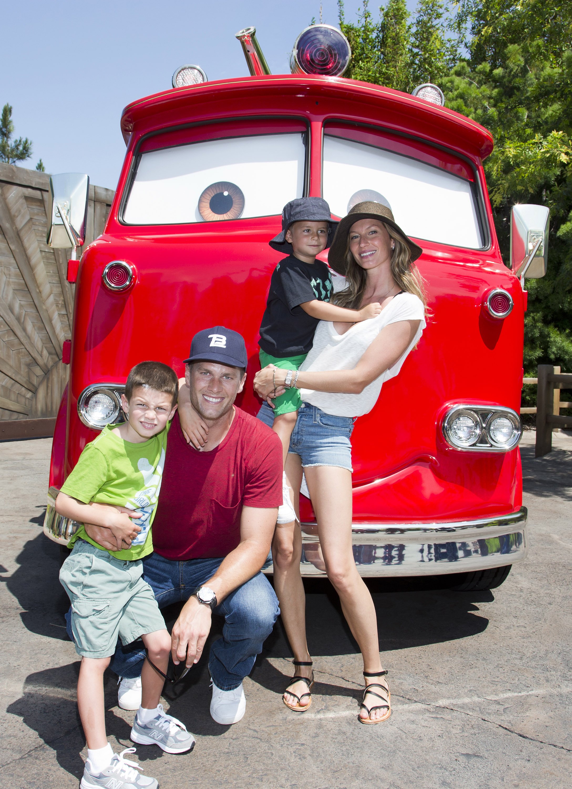 Tom Brady, his son Jack, 5, Gisele Bundchen, and their son Benjamin, 3, pose with Red the Fire Truck at Cars Land at Disney California Adventure park on July 2, 2013, in Anaheim, California. | Source: Getty Images