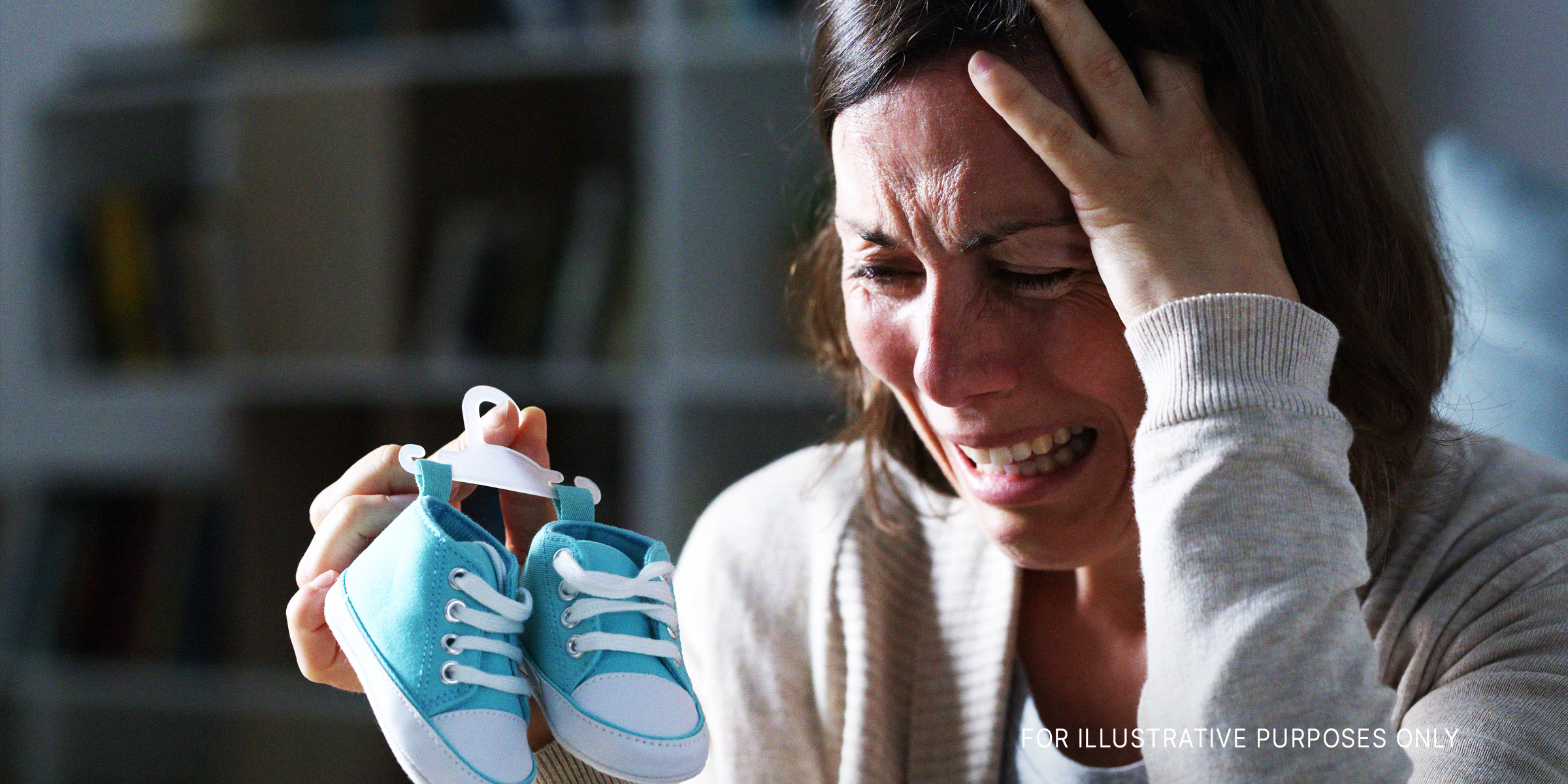 A woman crying while holding baby shoes | Source: Shutterstock