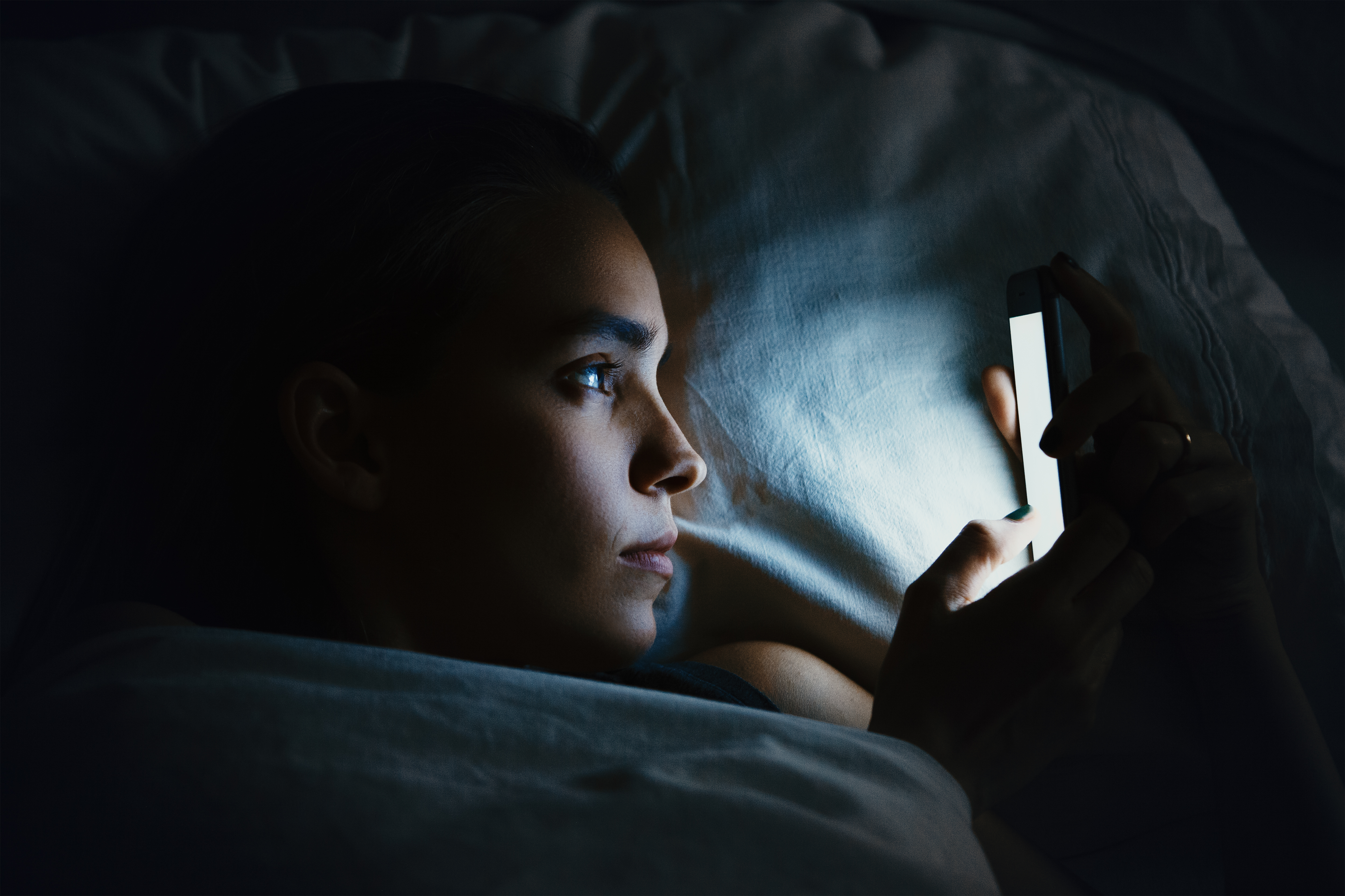 A young woman using a mobile phone in a bed | Source: Shutterstock