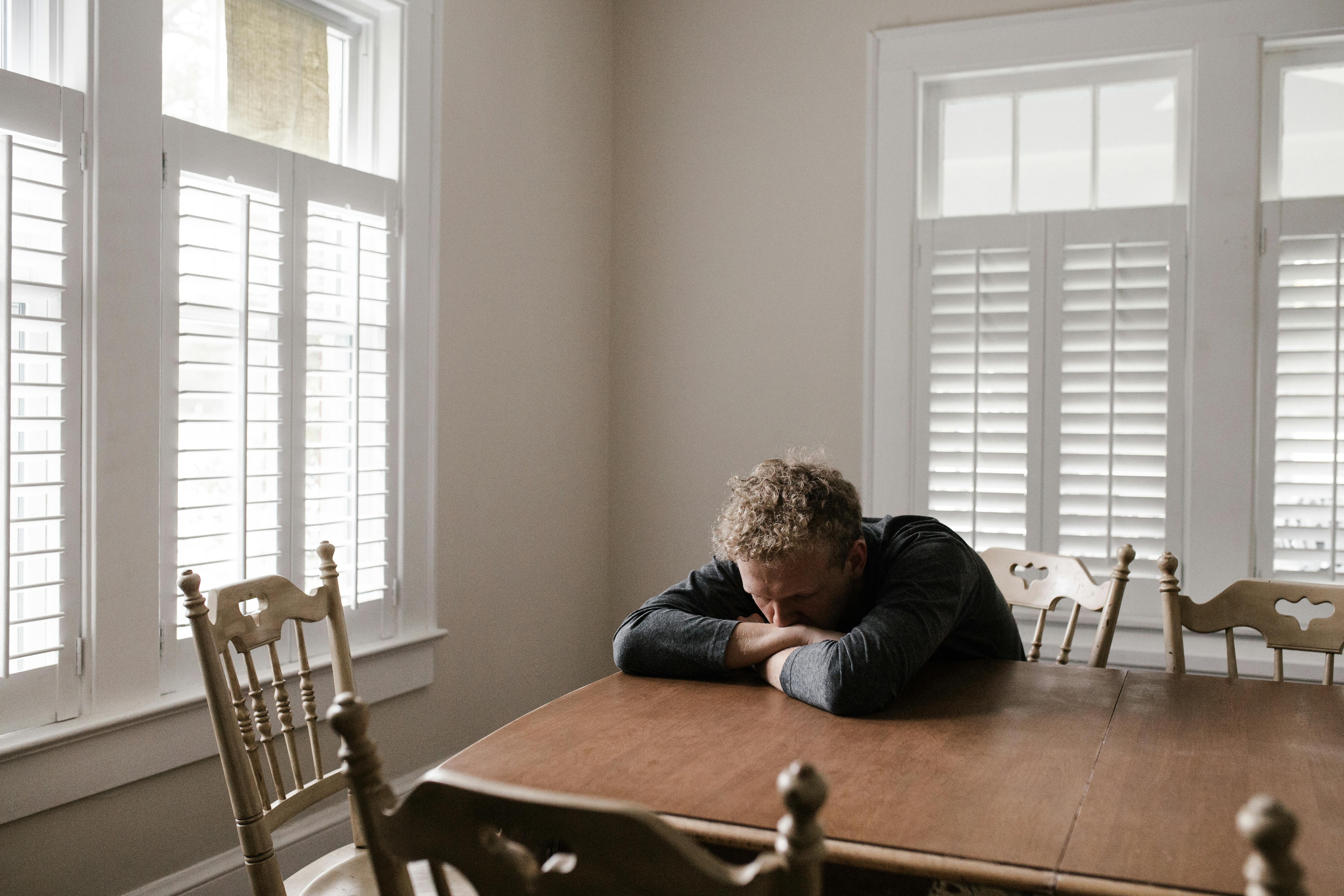 Man in gray long sleeve shirt sits on brown wooden chair | Source: Pexels