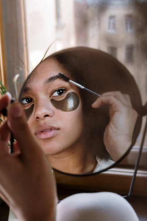 Mujer sosteniendo un espejo mientras maquilla sus pestañas. | Foto: Pexels Mujer sosteniendo un espejo mientras maquilla sus pestañas. | Foto: Pexels