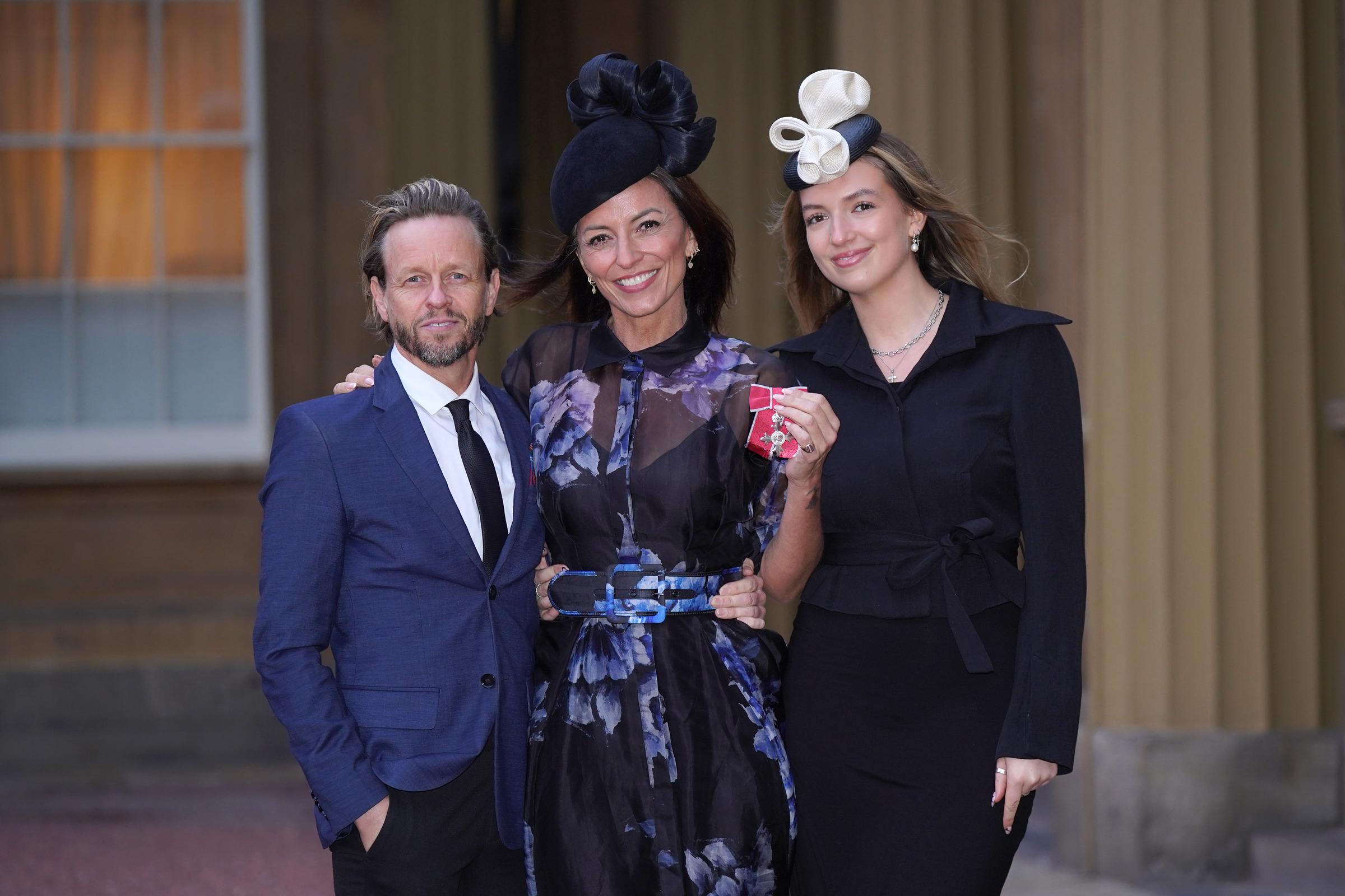 Davina McCall with her partner, Michael Douglas, and her daughter, Holly Robertson, after being made a Member of the Order of the British Empire on January 31, 2024, in London, England. | Source: Getty Images