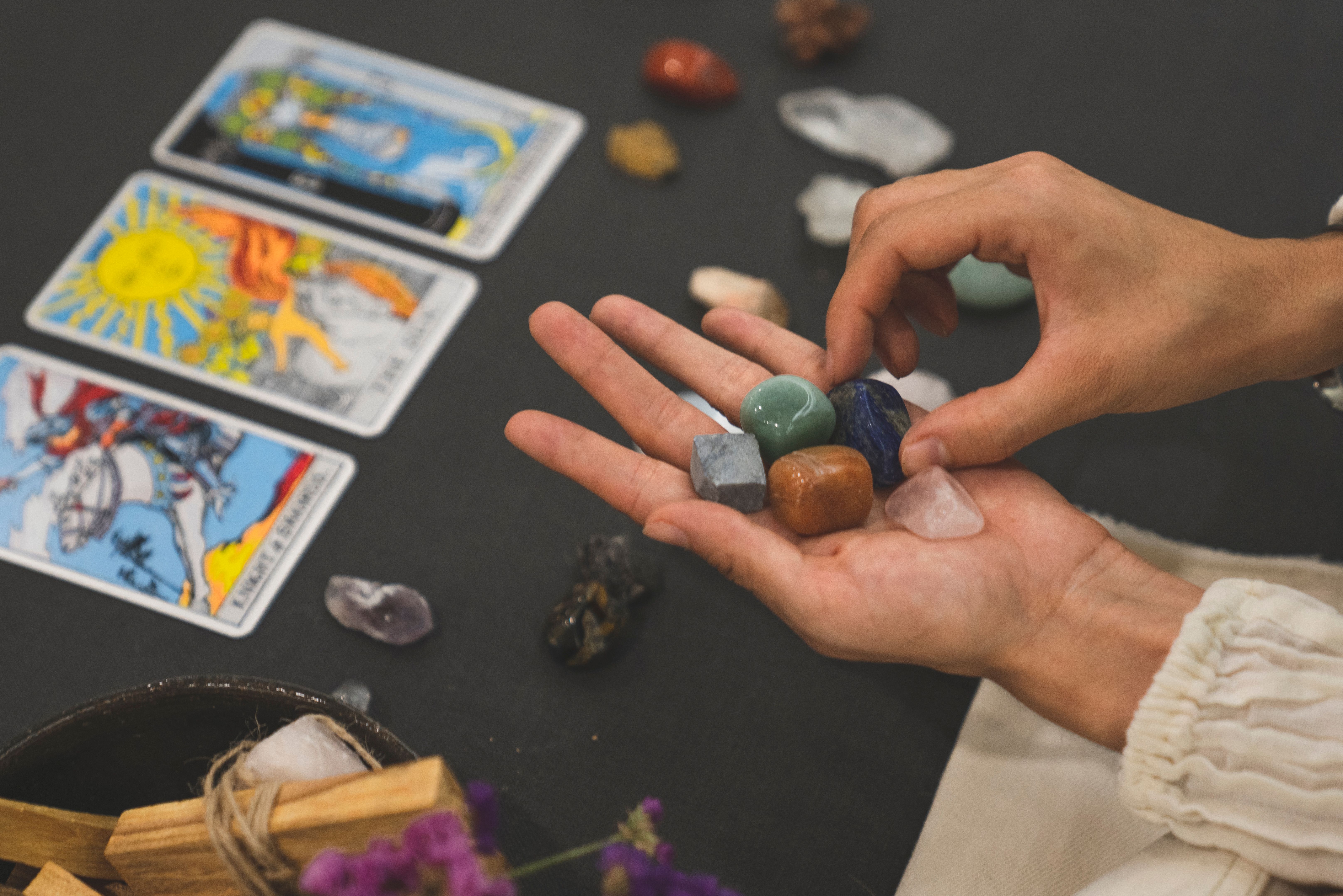 Person holding healing crystals with tarot cards in the background | Source: Pexels