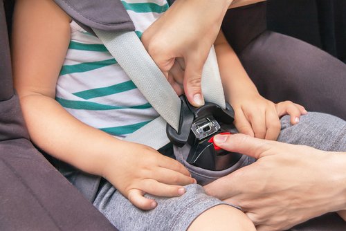 Mamá ajustando el cinturón de seguridad de un niño en el asiento trasero. | Foto: Shutterstock