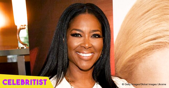 Kenya Moore shows off her growing baby bump in white midi-dress with leggy thigh-slit in new pic